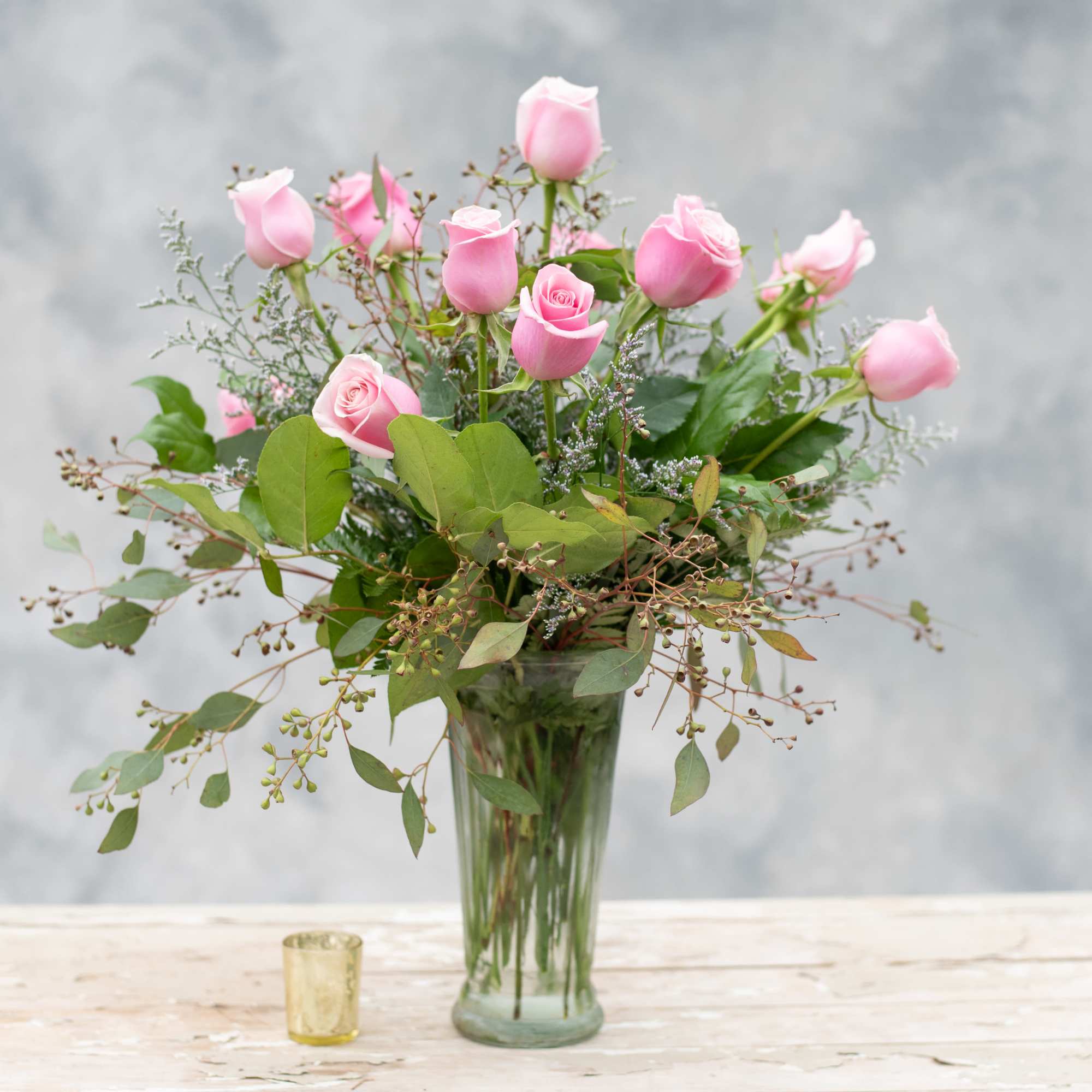 One dozen long stemmed pink roses classically arranged in a tall, tapered