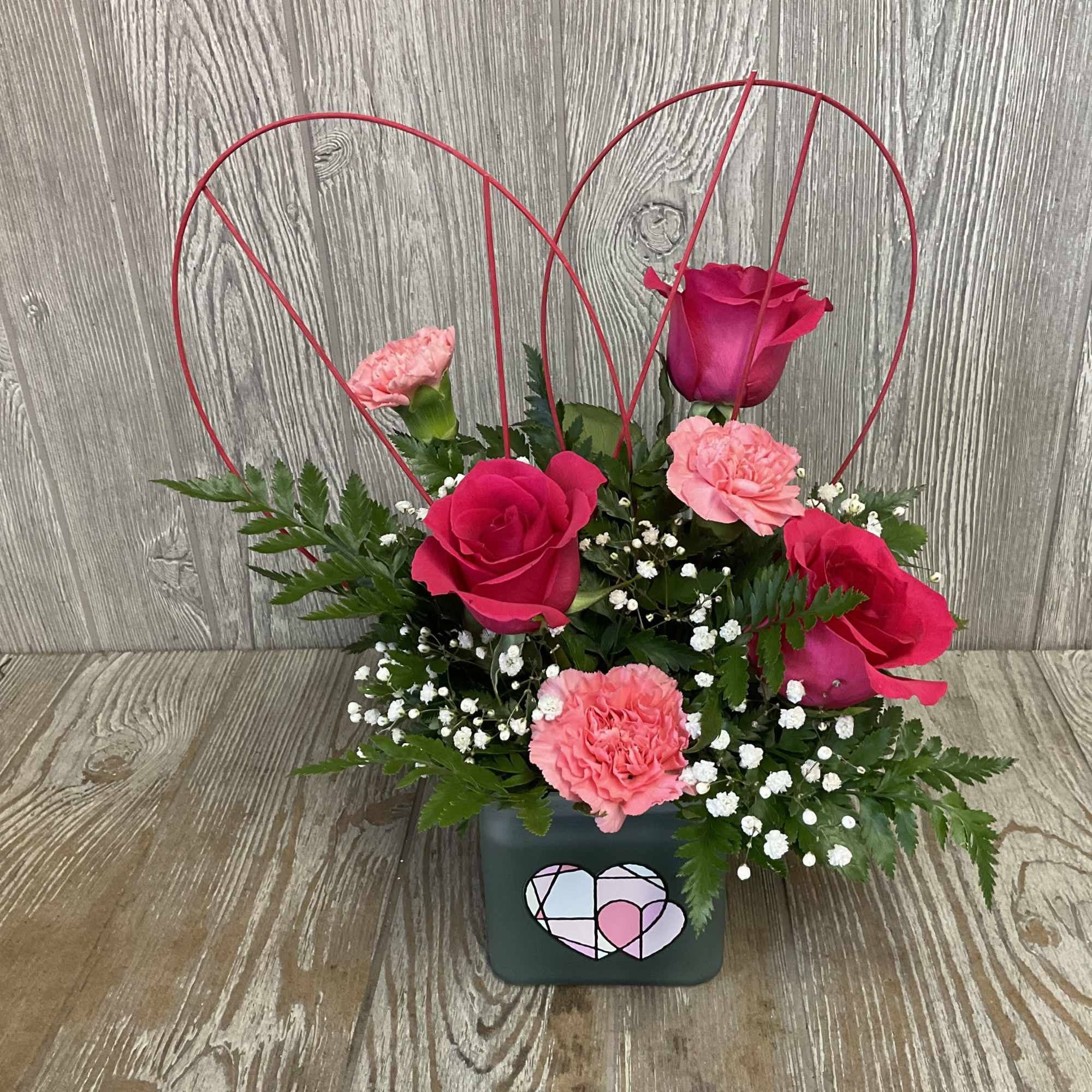 Modern and beautiful arrangement of roses in a decorative, geometric heart container. Modern and beautiful arrangement of roses in a decorative, geometric heart container.