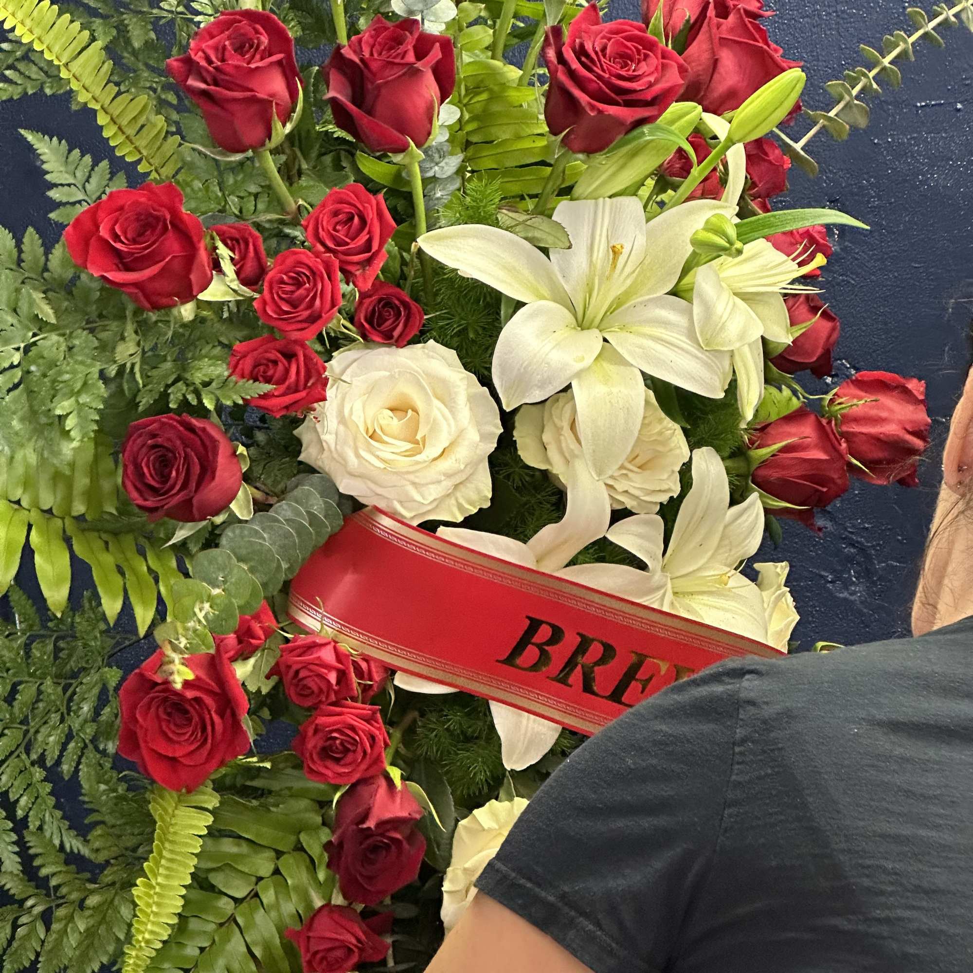 Red roses and white lilies designed with delicate greens. Optional ribbon with