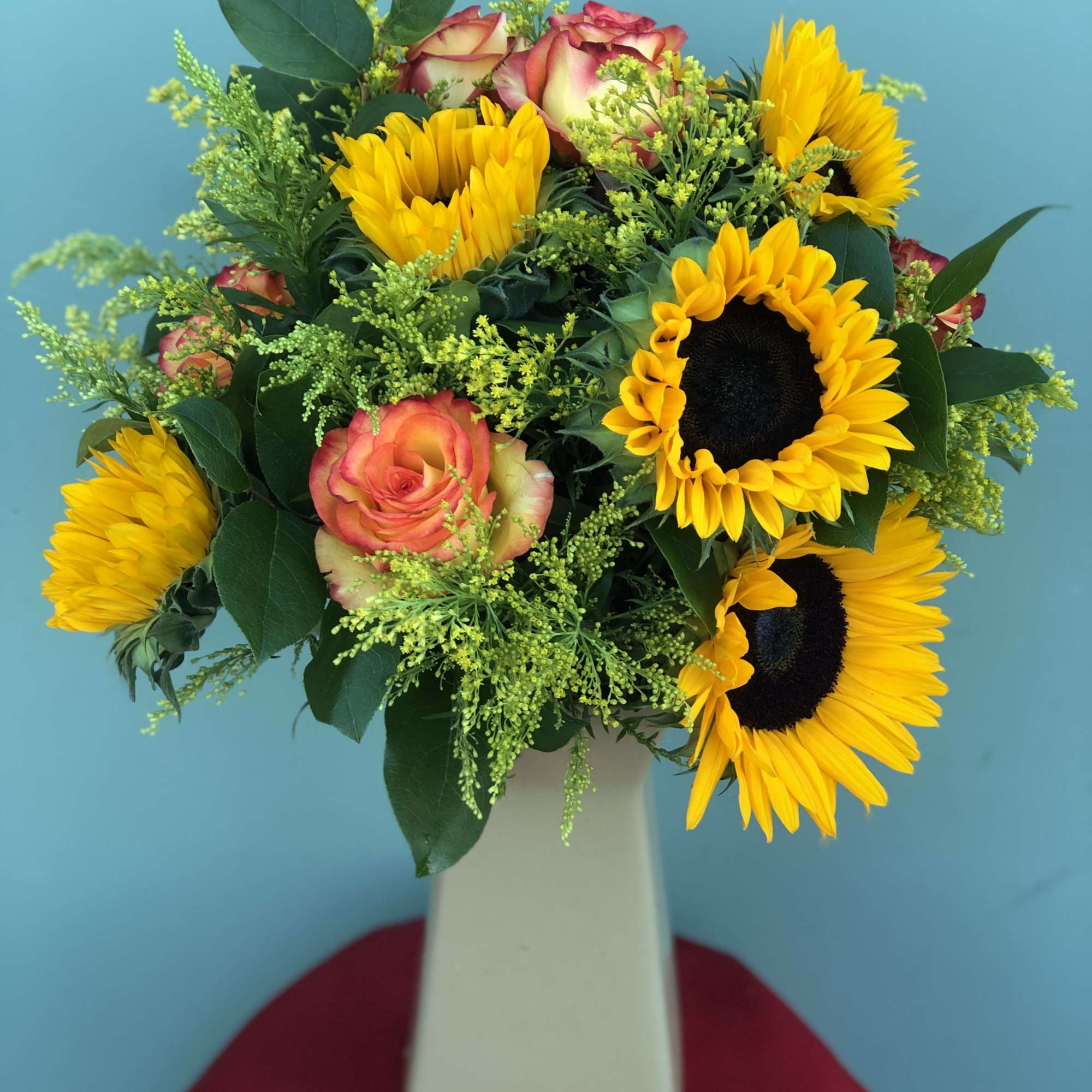 Sunflowers, Roses, and filler blend with one another to bring this arrangement