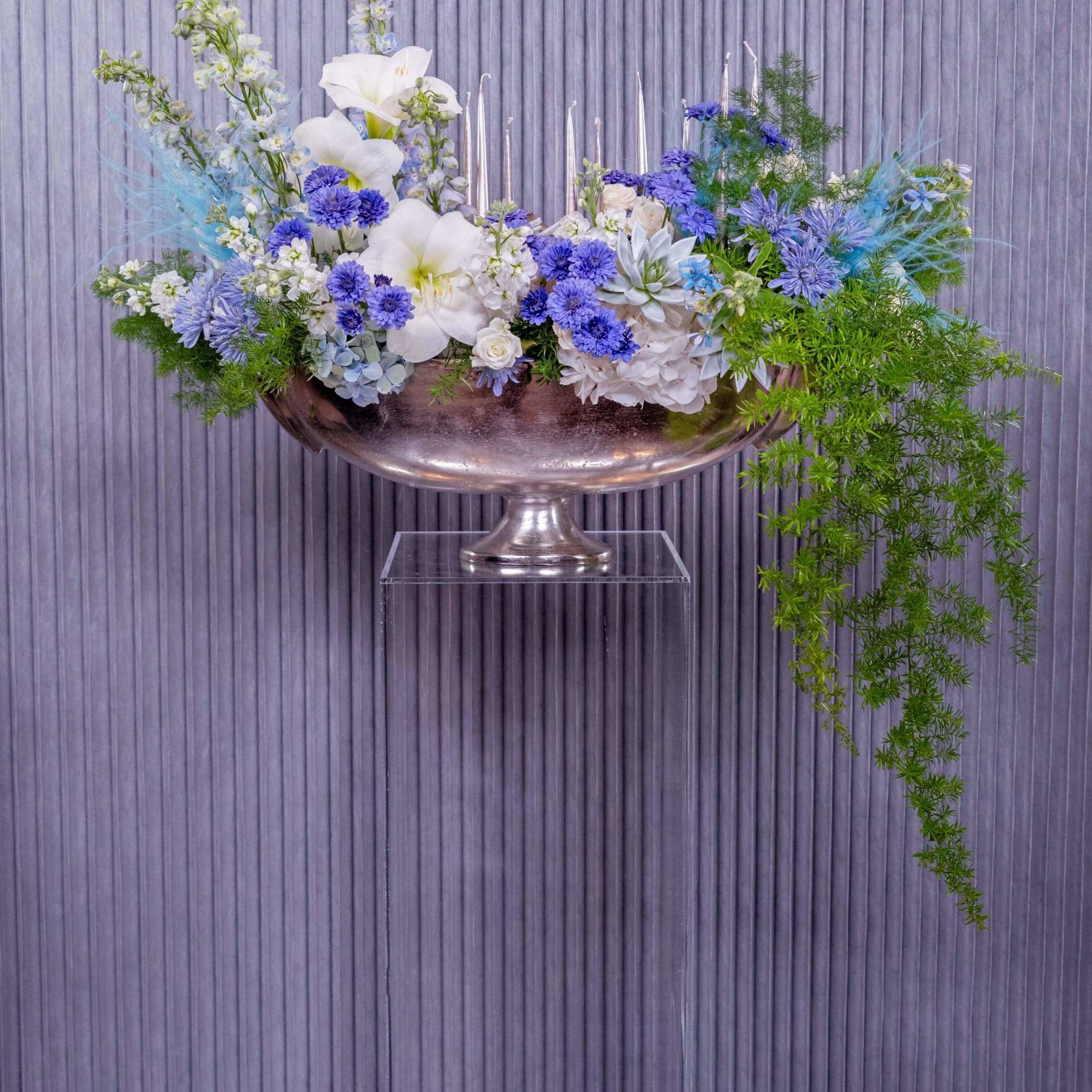 The Blue Serenity Menorah Arrangement is a refined, elegant centerpiece designed to