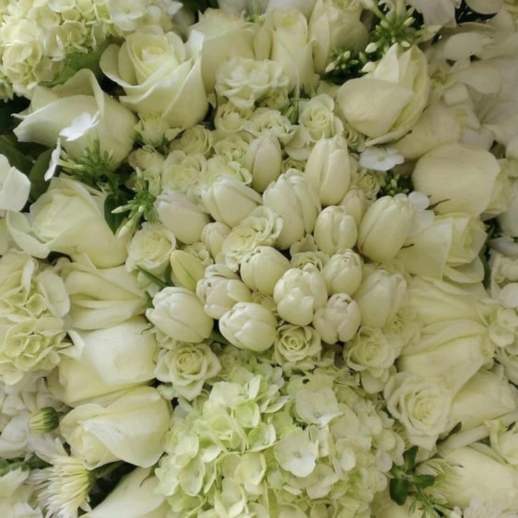 White funeral standing spray featuring orchids, roses, and a variety of seasonal