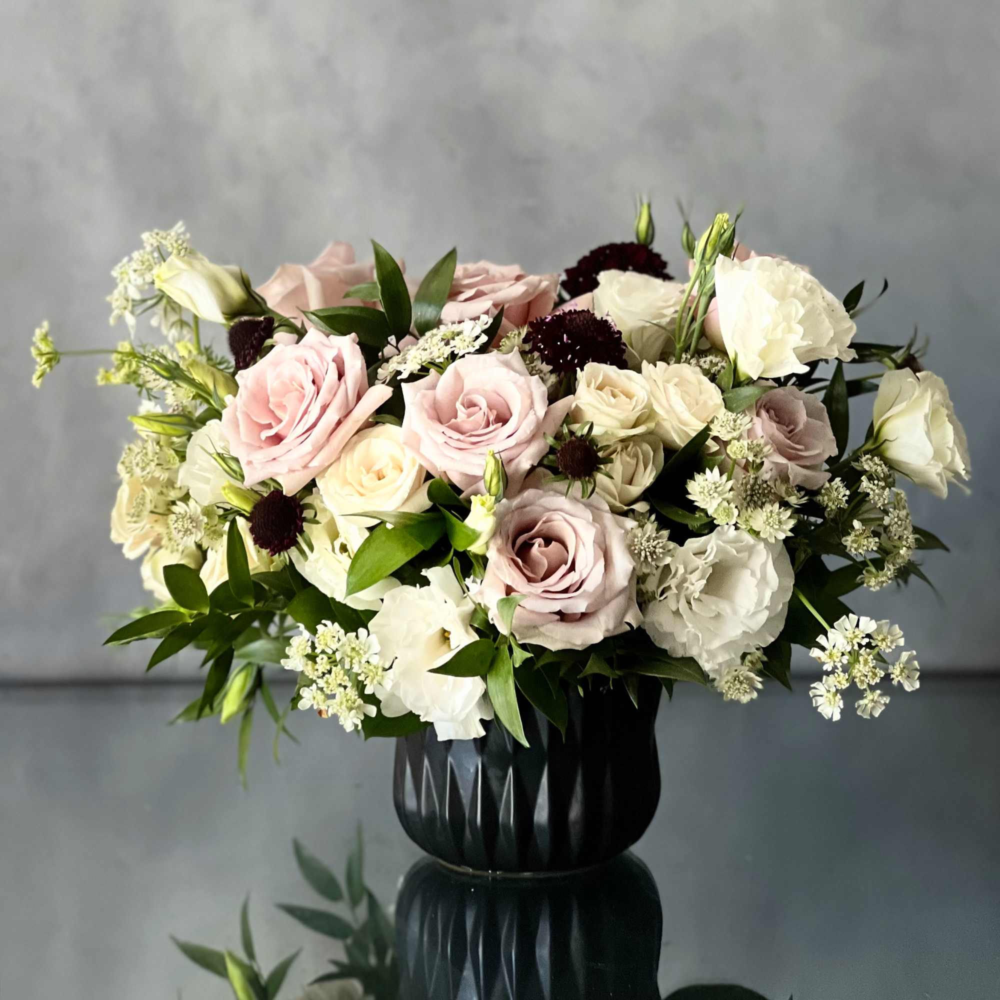 Our beautiful arrangement consists of White and light lavender Roses, Thistles and