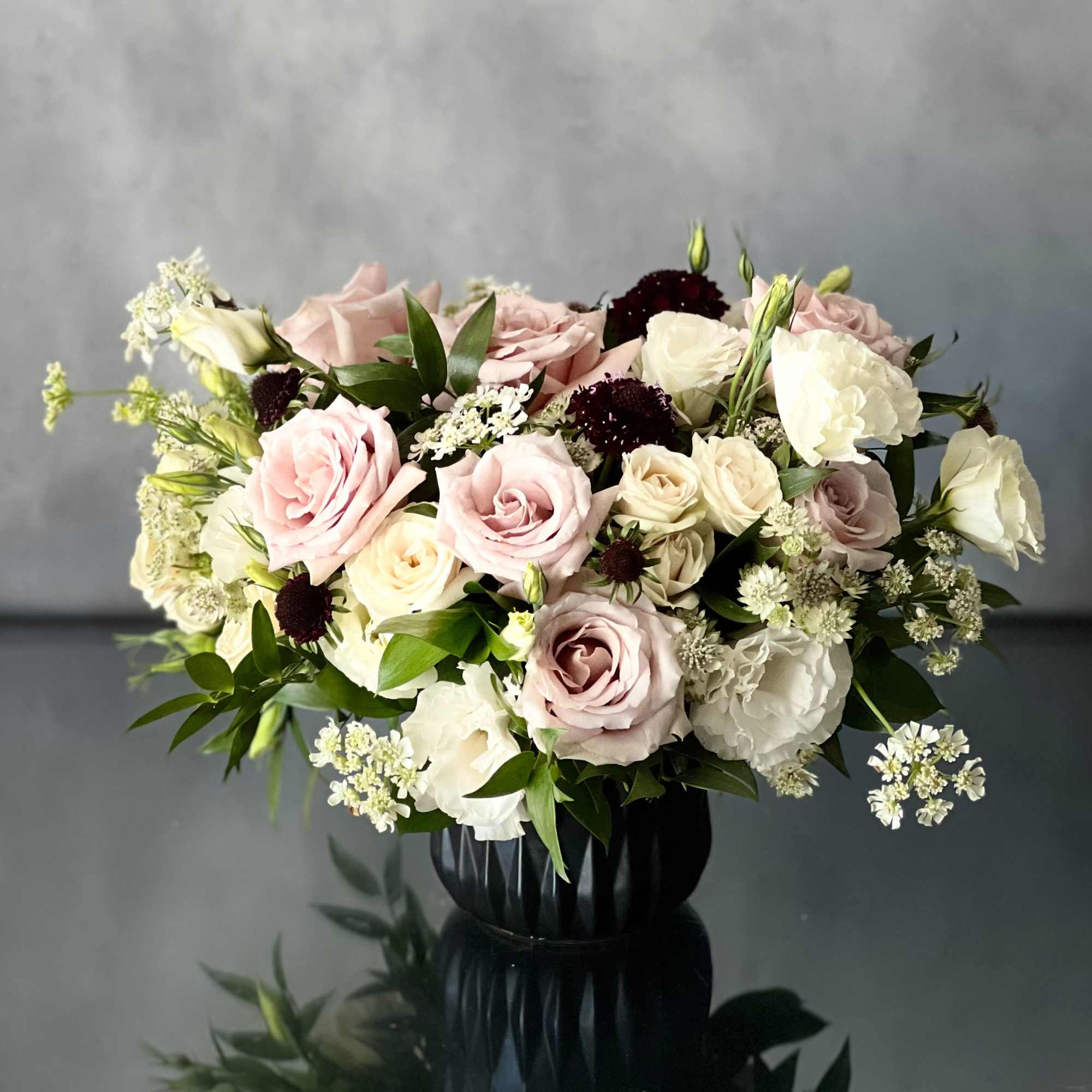 Our beautiful arrangement consists of White and light lavender Roses, Thistles and