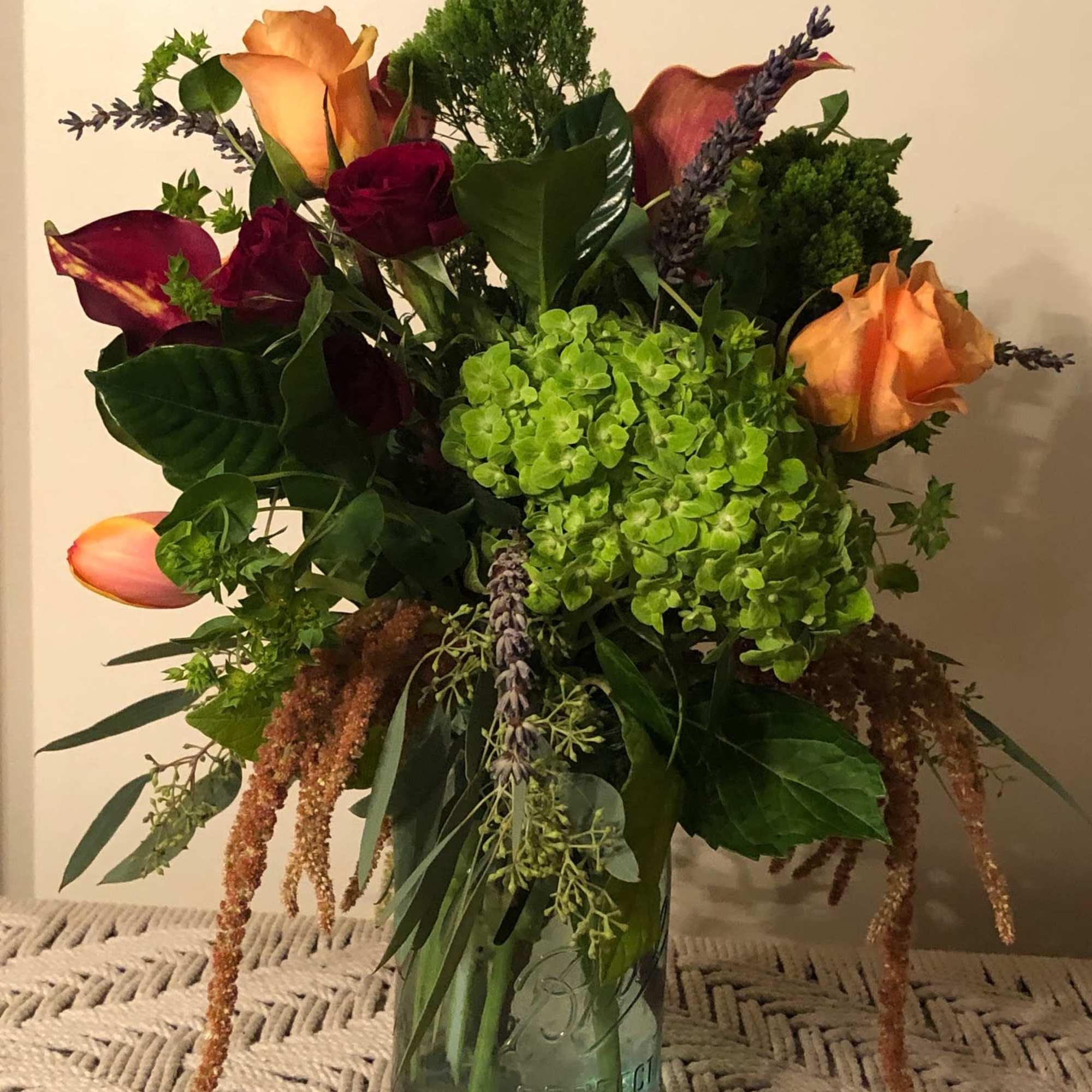 A rich, jewel colored arrangement of burgundies paired with orange, tangerine, vibrant