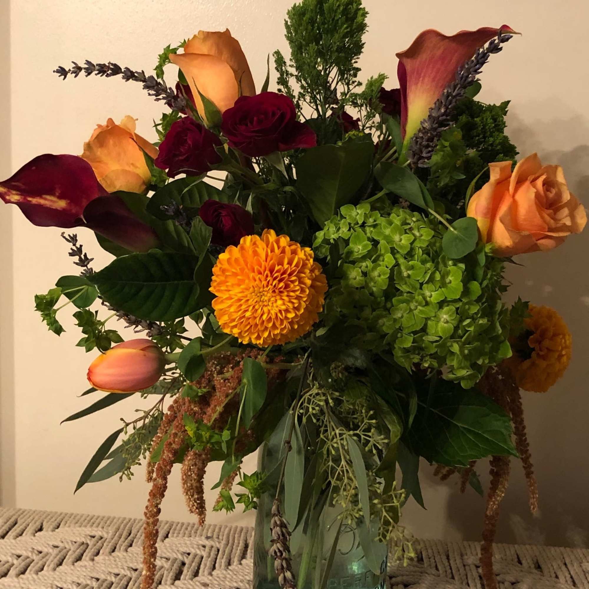 A rich, jewel colored arrangement of burgundies paired with orange, tangerine, vibrant