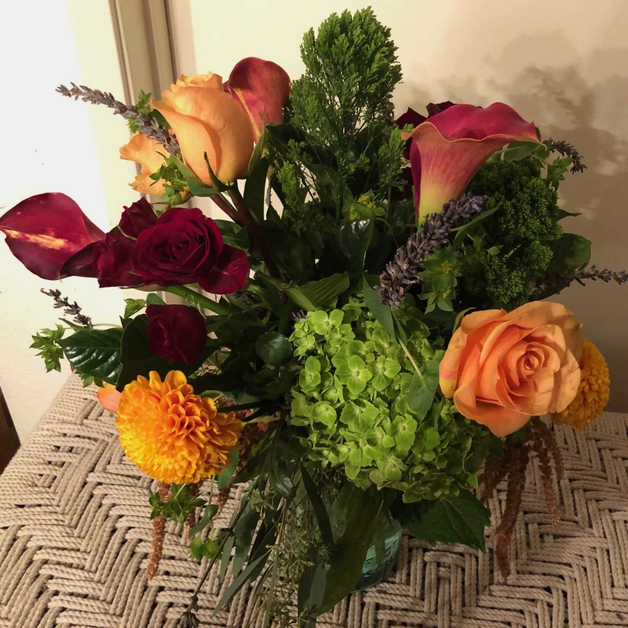 A rich, jewel colored arrangement of burgundies paired with orange, tangerine, vibrant