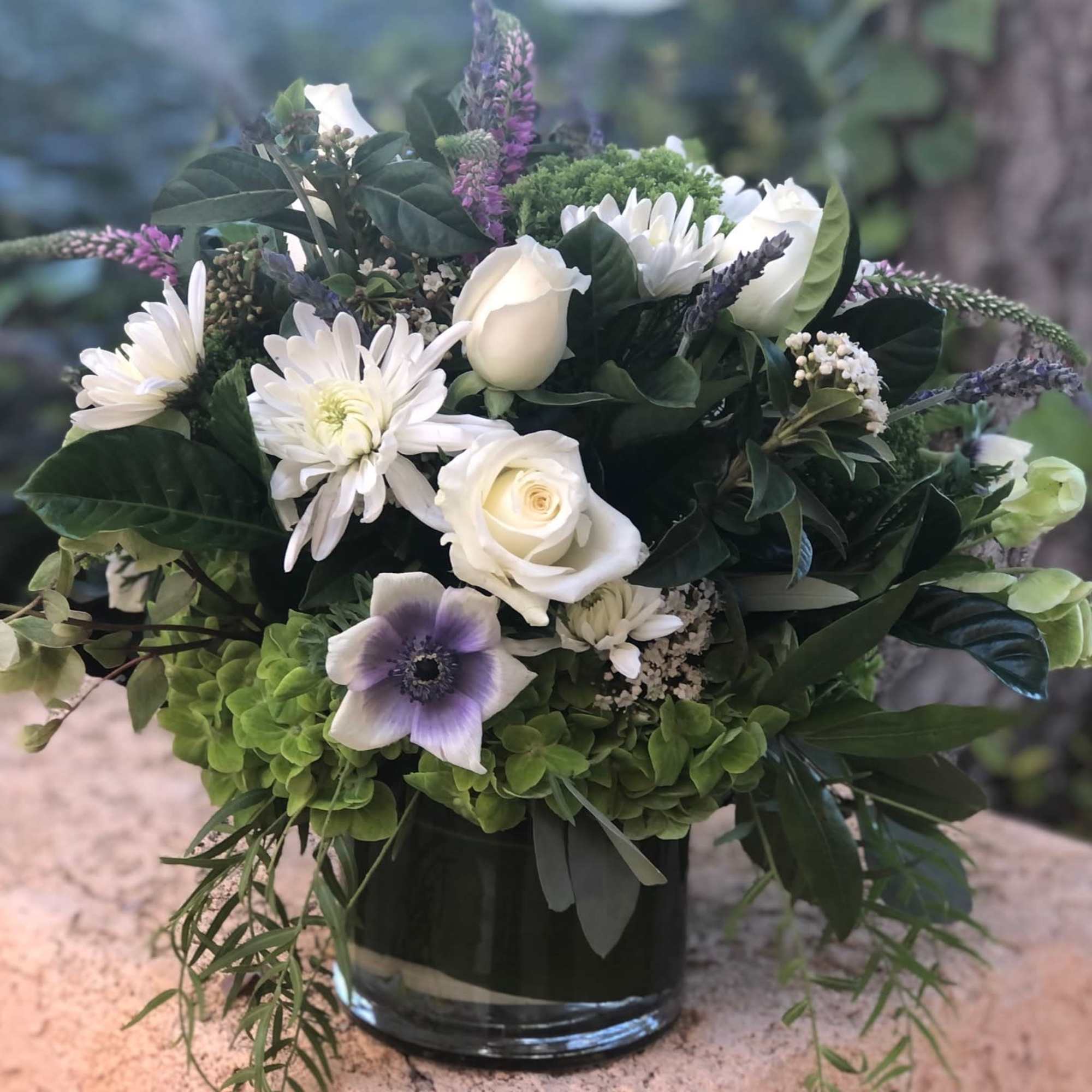 Green and white lush arrangement with accents of purple and lavender. Chunky