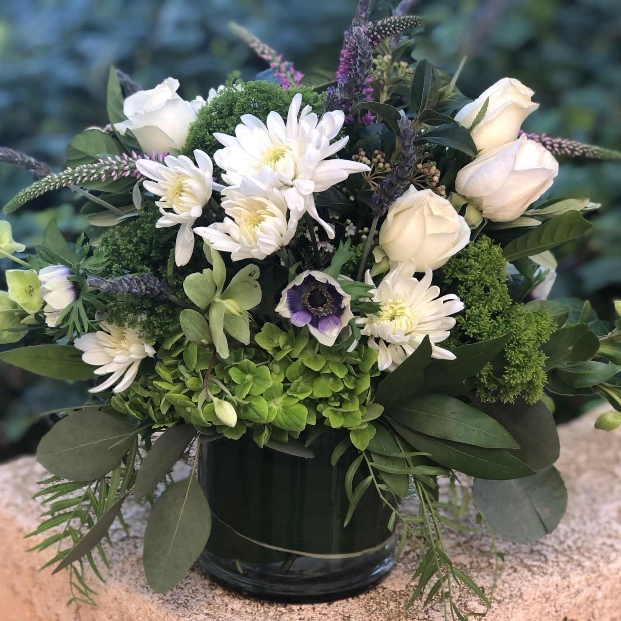 Green and white lush arrangement with accents of purple and lavender. Chunky