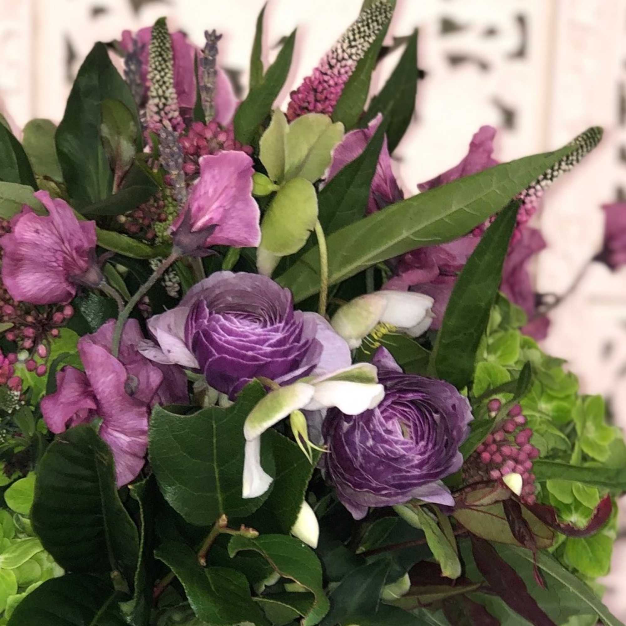 Lush assortment of purple flowers such as Ranunculus, Veronica, Sweet Pea and