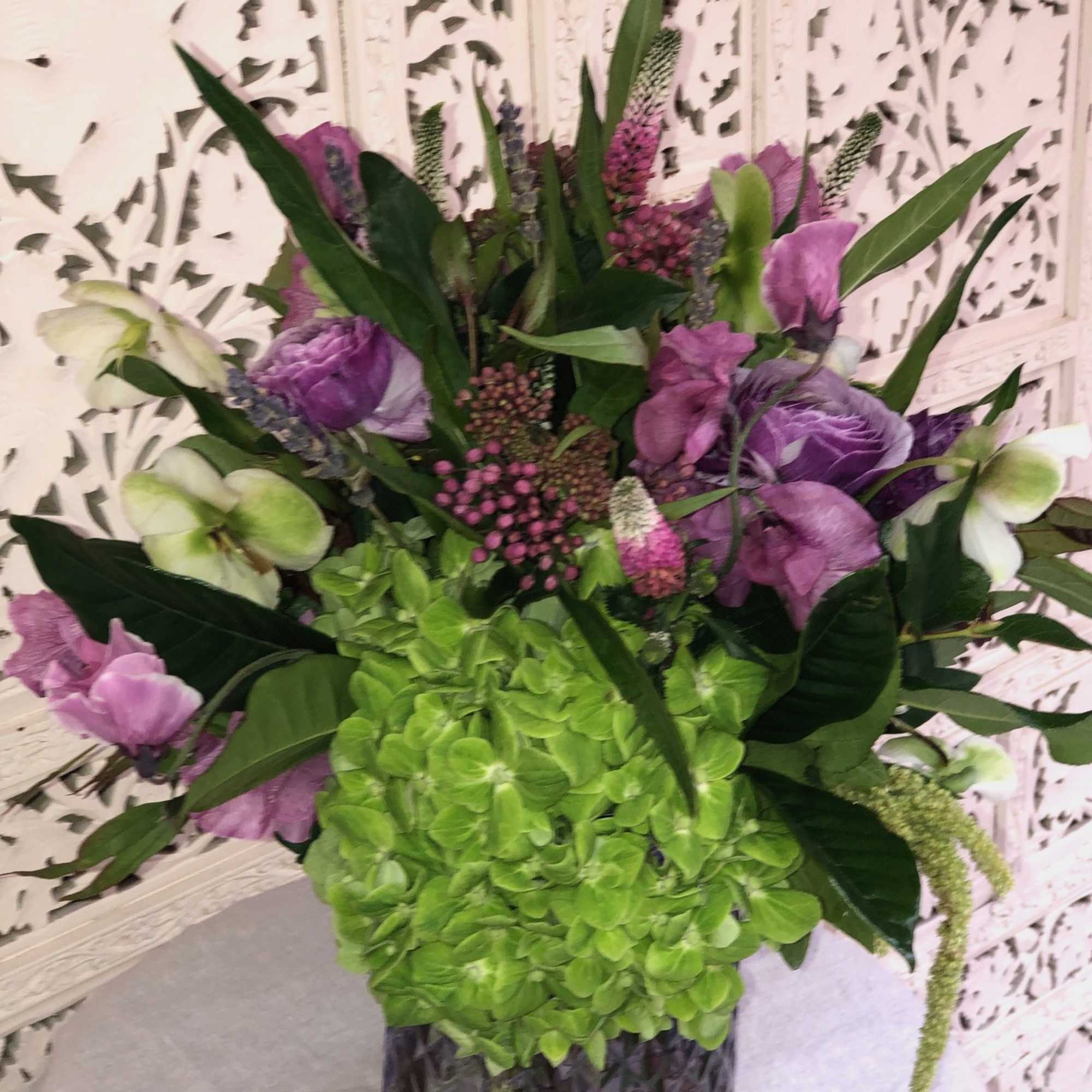 Lush assortment of purple flowers such as Ranunculus, Veronica, Sweet Pea and