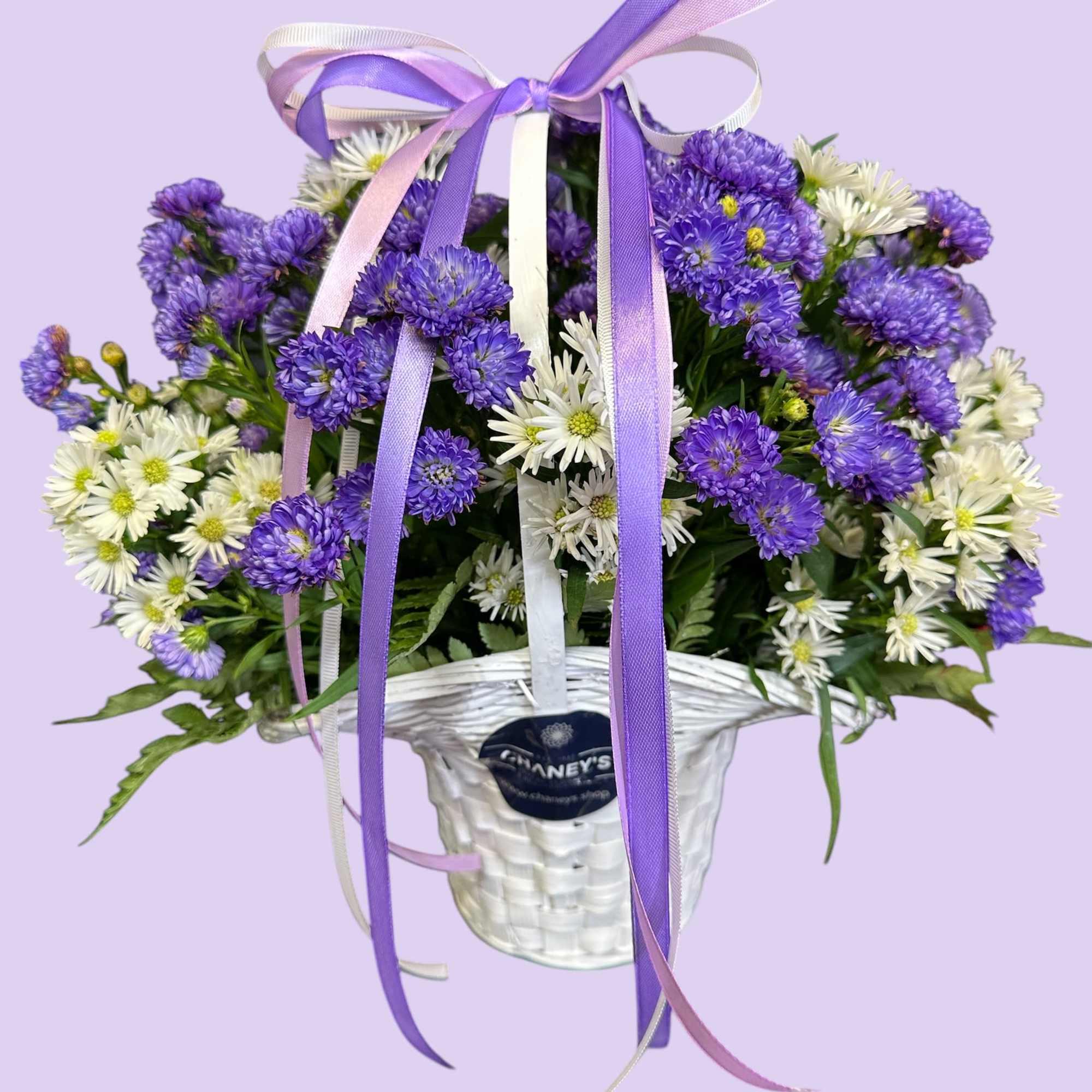 Purple and white fresh cut flowers in a white basket