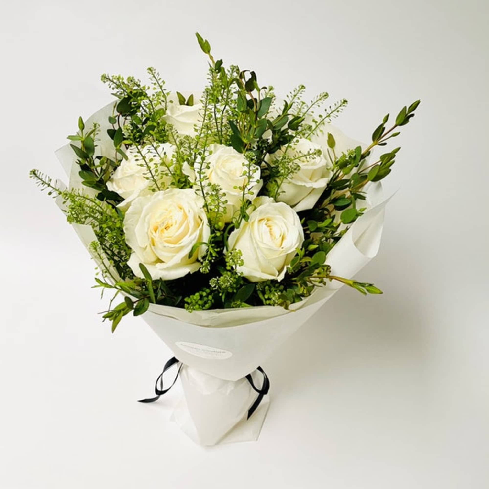 Simple white hand-tied bouquet featuring white roses. 