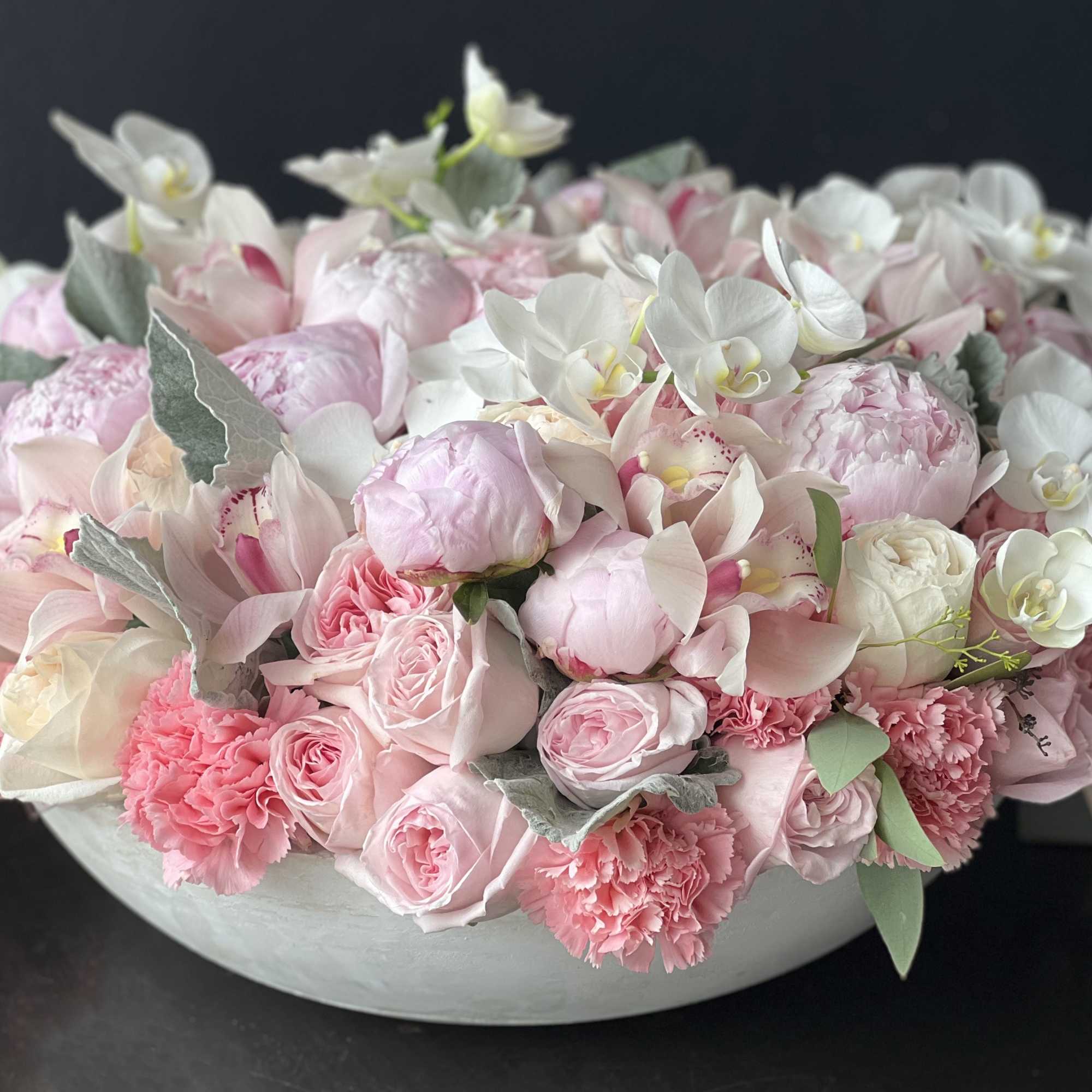 Large cement vase with mixed flowers. Large, lavish arrangement with roses, garden