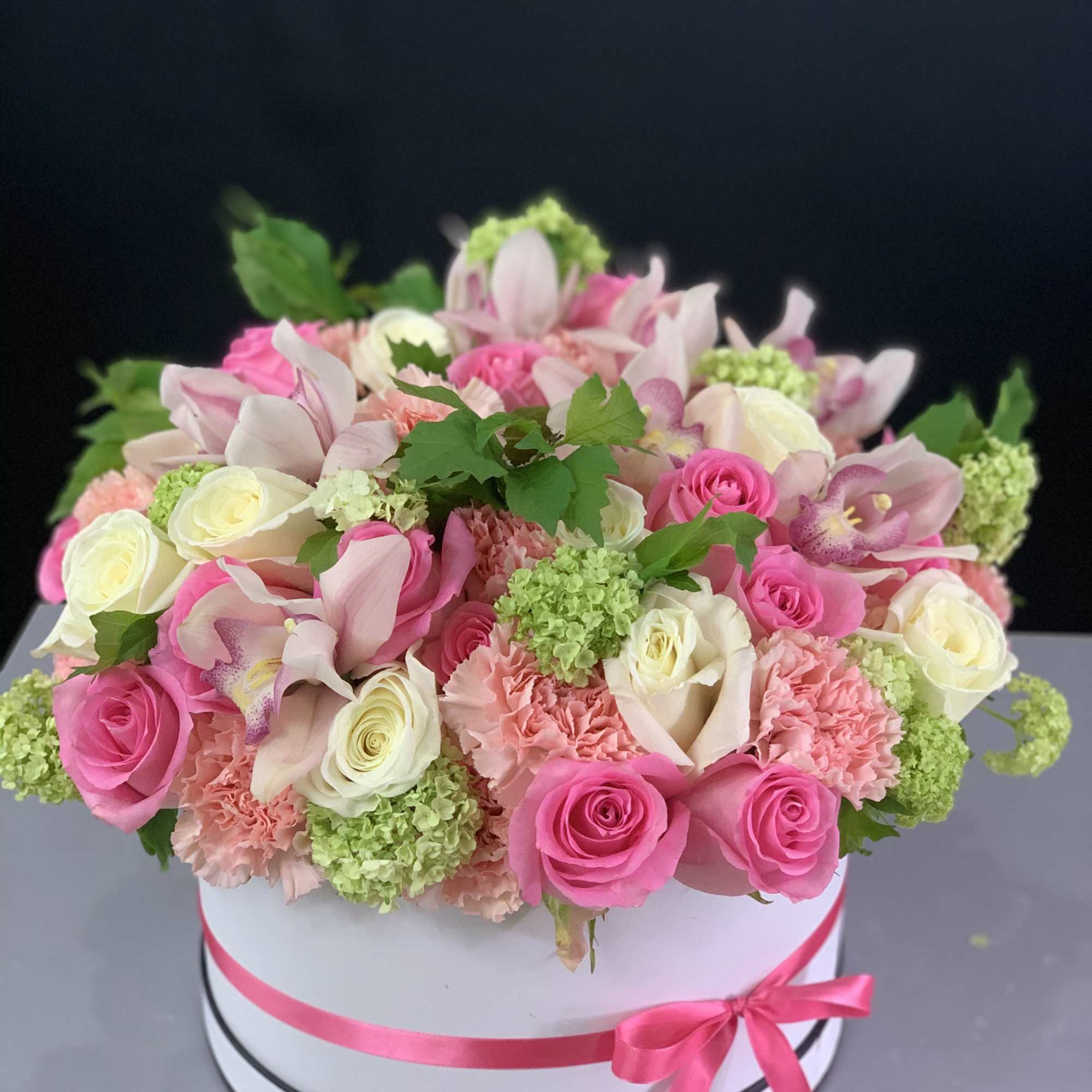 Delicate flower arrangement with pink roses, white cymbidium and mix seasonal flowers.