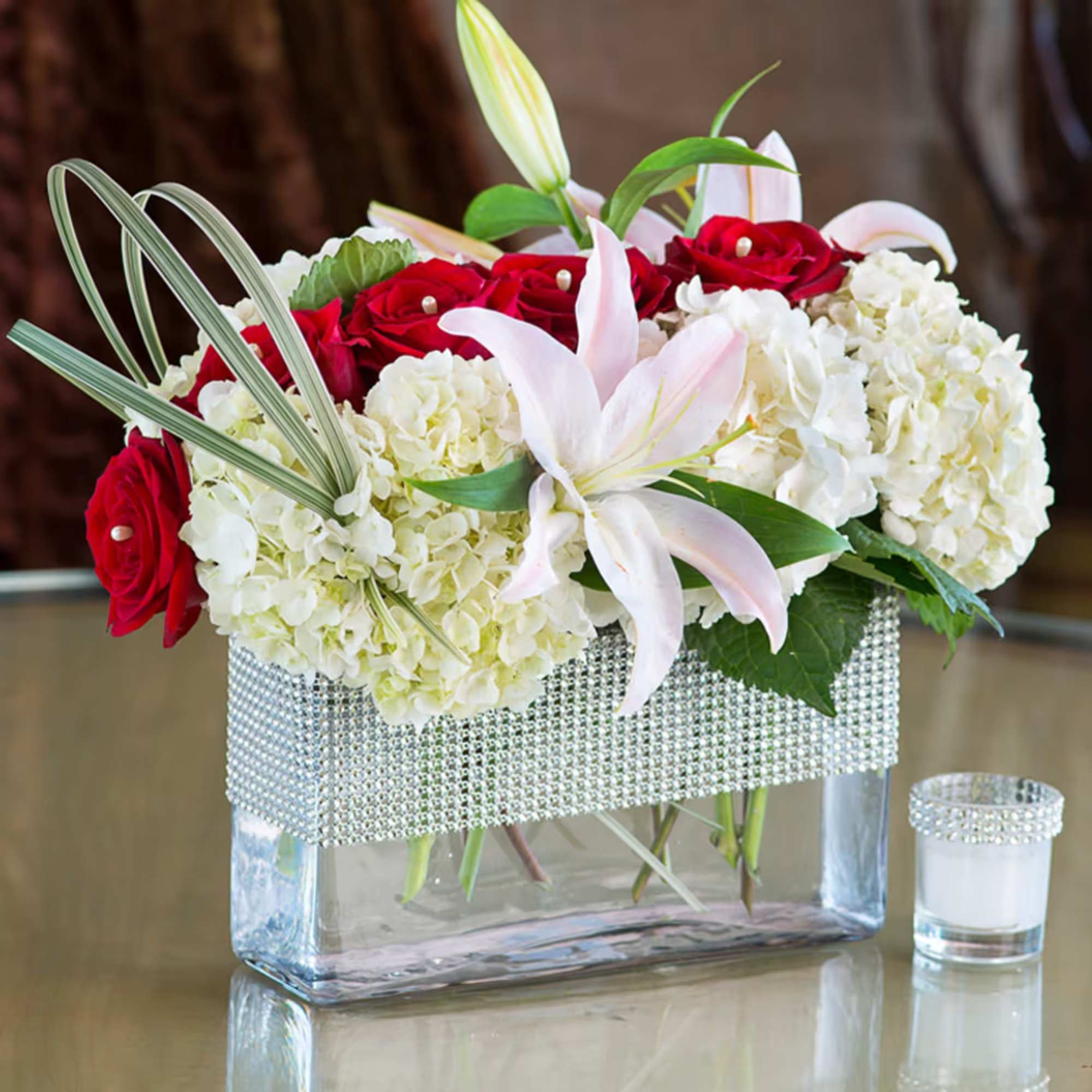 An exquisite bouquet with red roses, lilies and hydrangeas accented with glittering