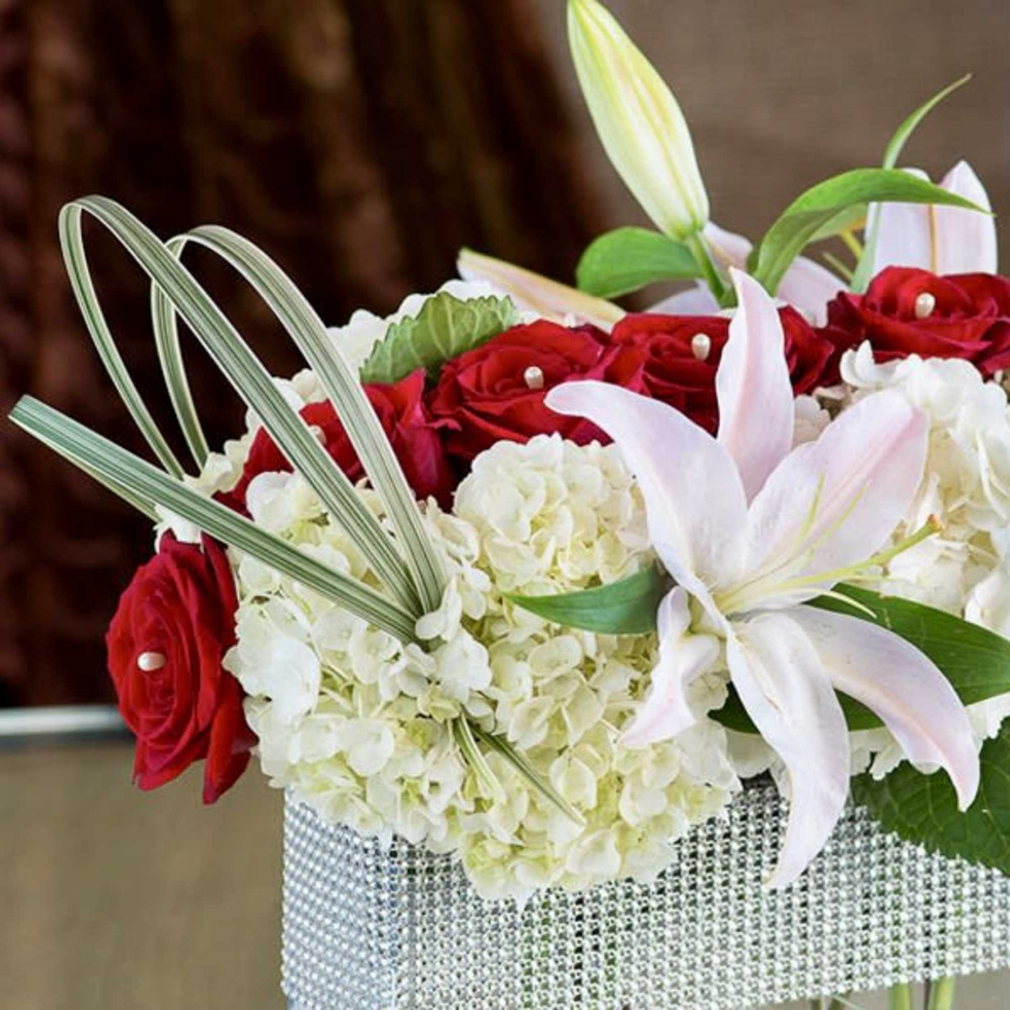 An exquisite bouquet with red roses, lilies and hydrangeas accented with glittering