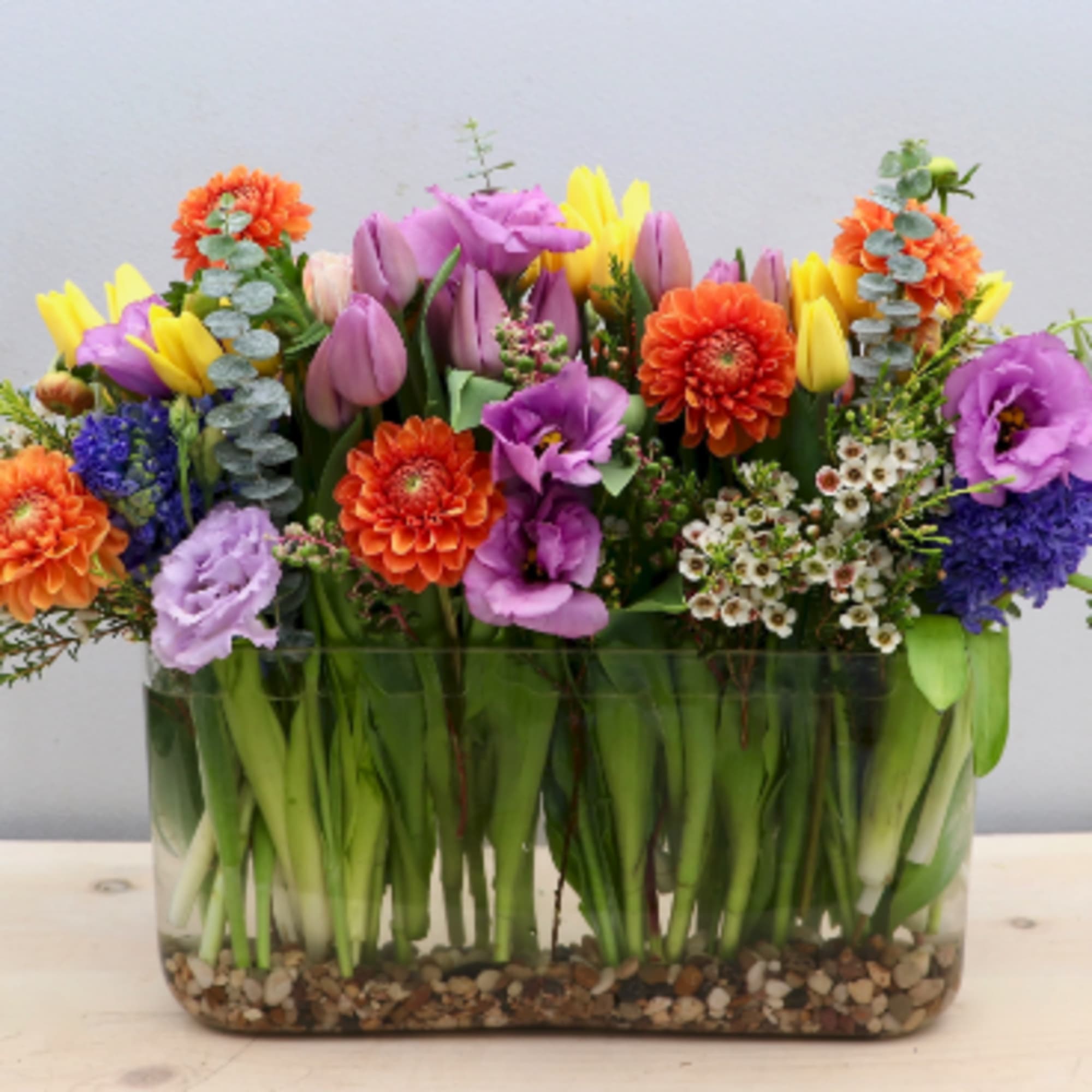 All of springs best in our rectangular vase. Seasonal greens accent tulips