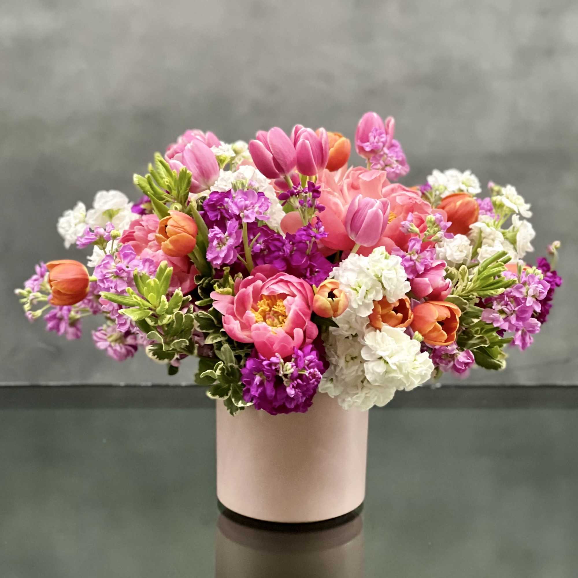 Lush tones of pink, orange and lavender seasonal blooms which includes peonies