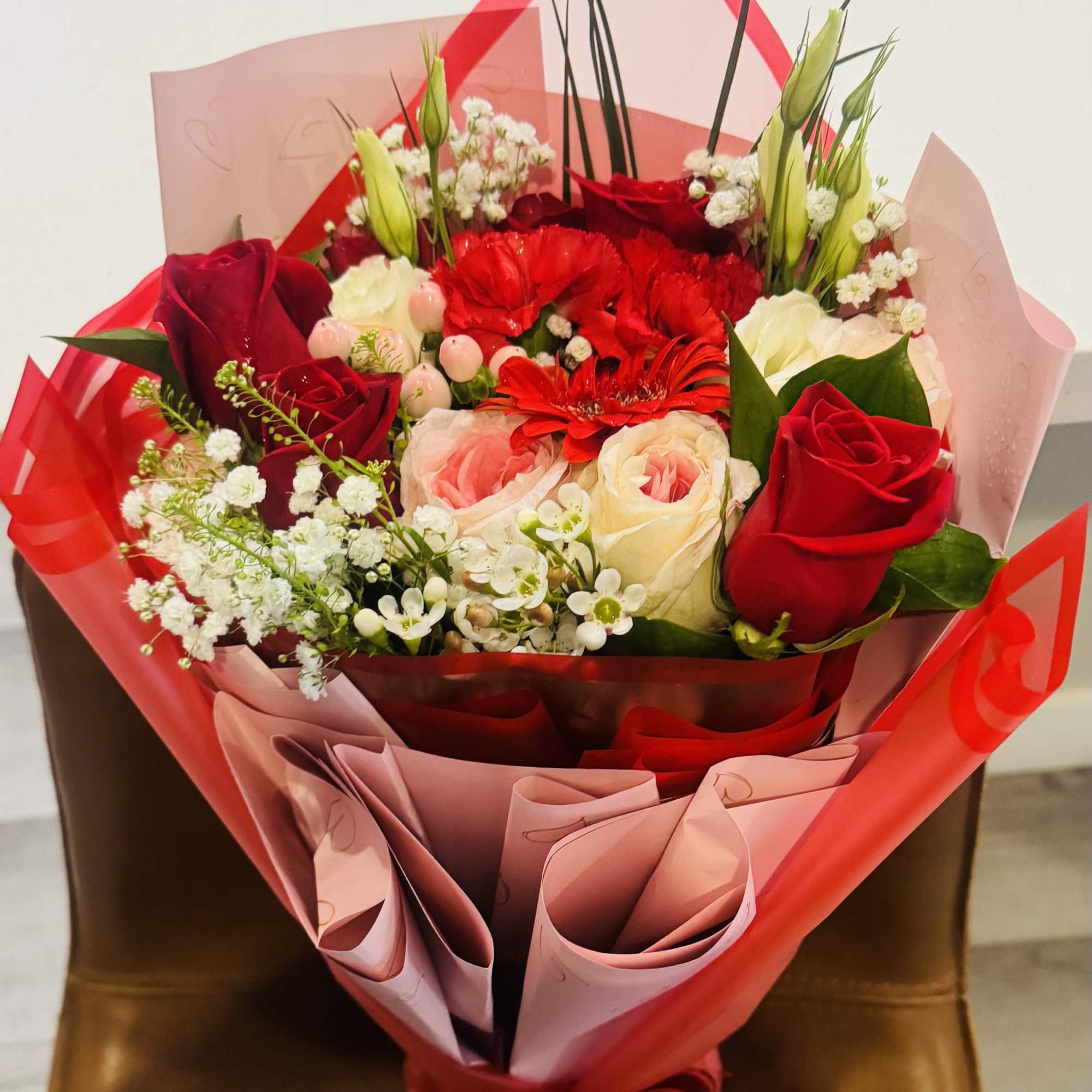 A gorgeous mix of Red roses, Pink Roses, wax flower, Lisianthus and