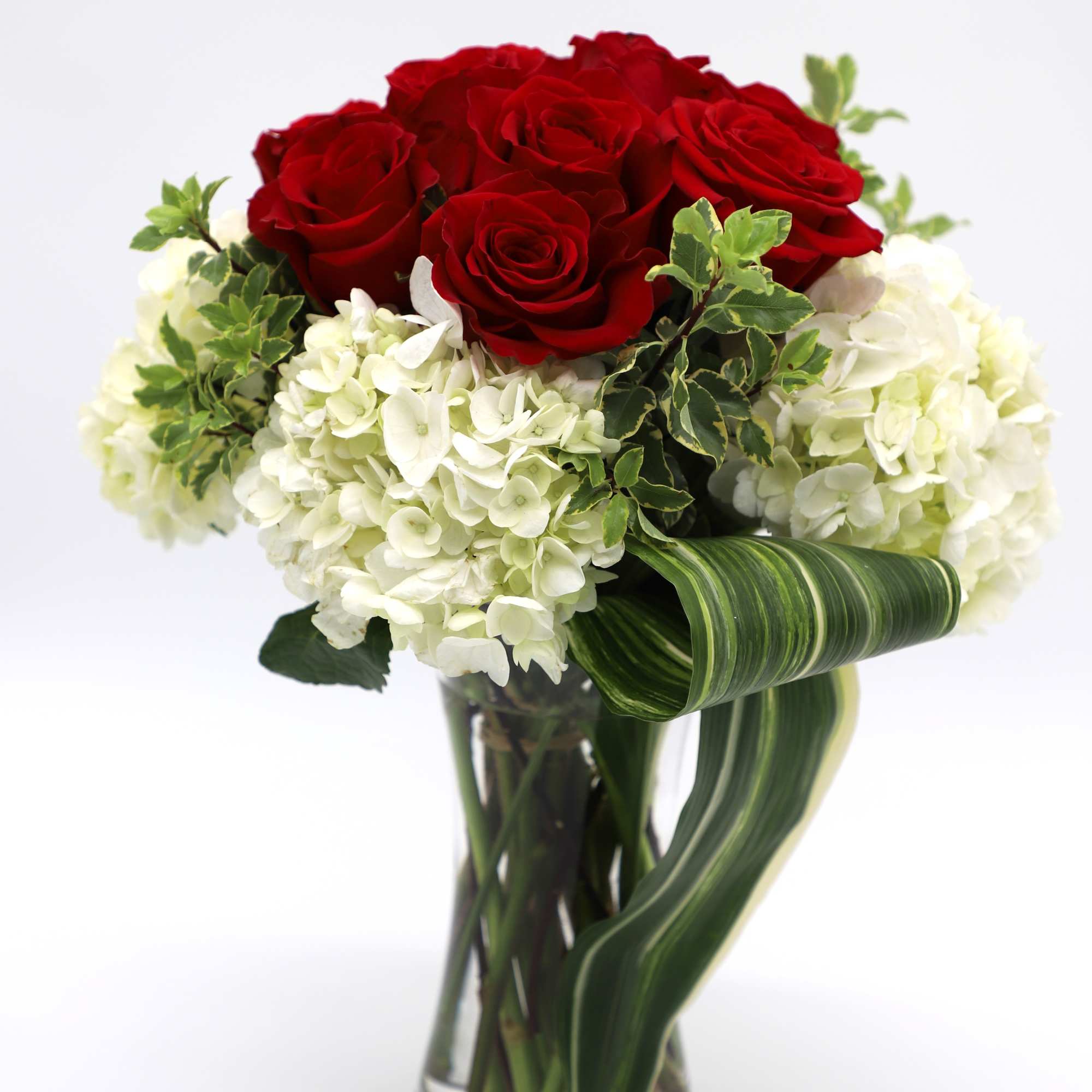 A sweet arrangement made with red roses and mini hydrangeas in a