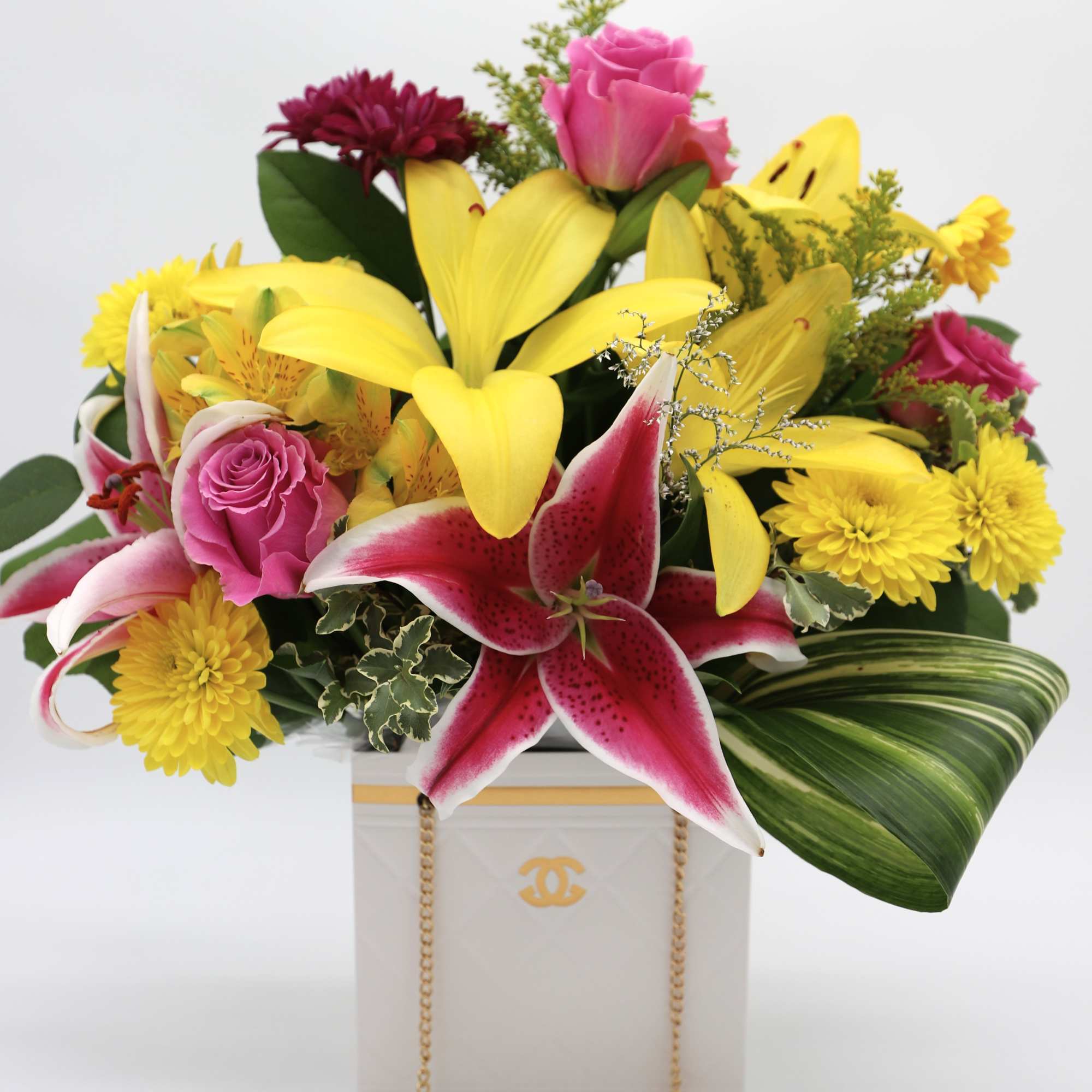 A beautiful arrangement made with roses, mums, lilies and greenery made in