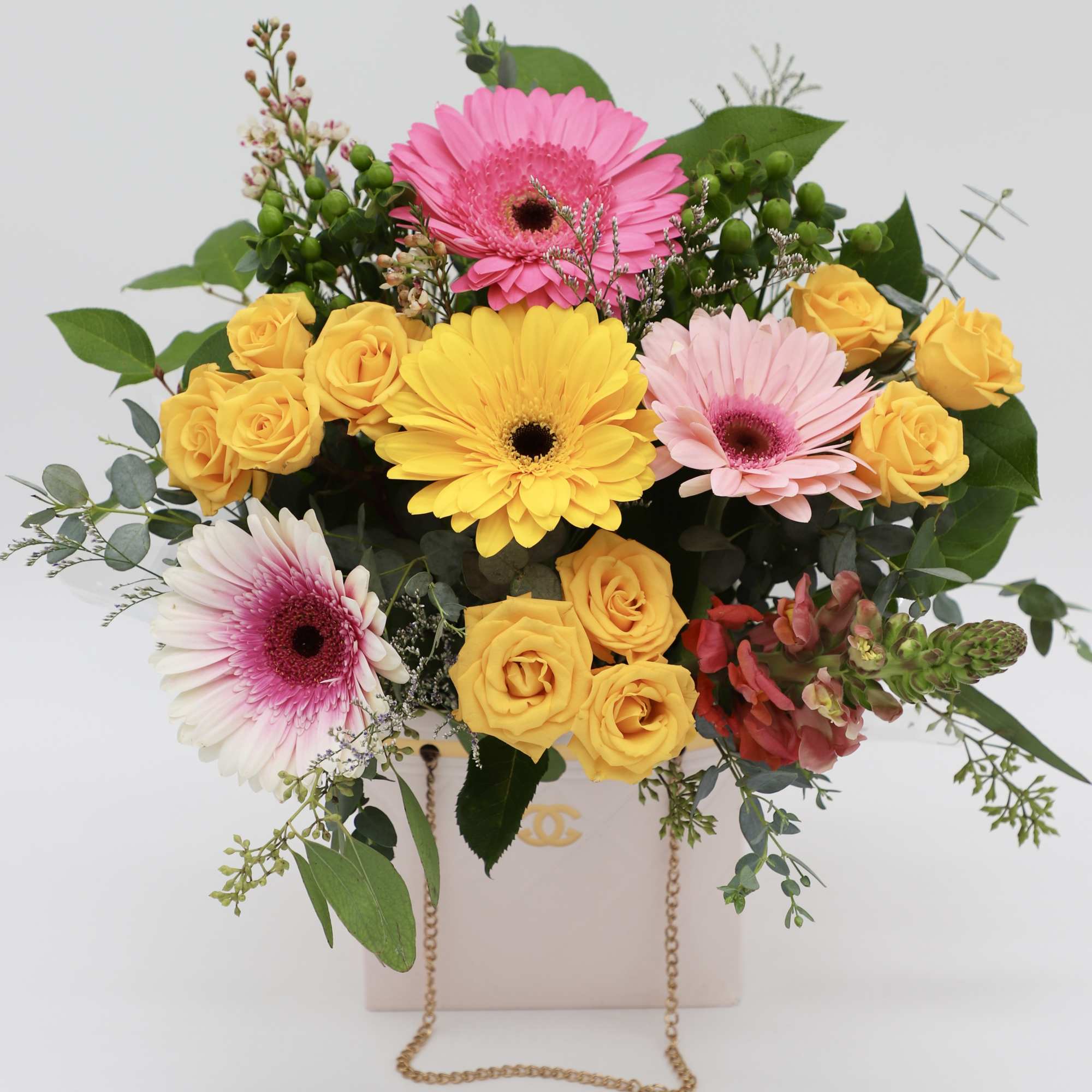 A beautiful arrangement made with gerber daisies, spray roses, and greenery made