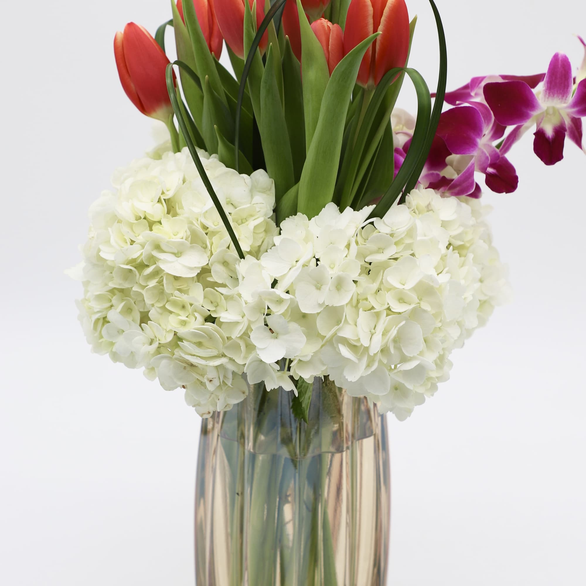 A vintage styled glass with carefully placed hydrangea, tulips, and dendrobium orchids.