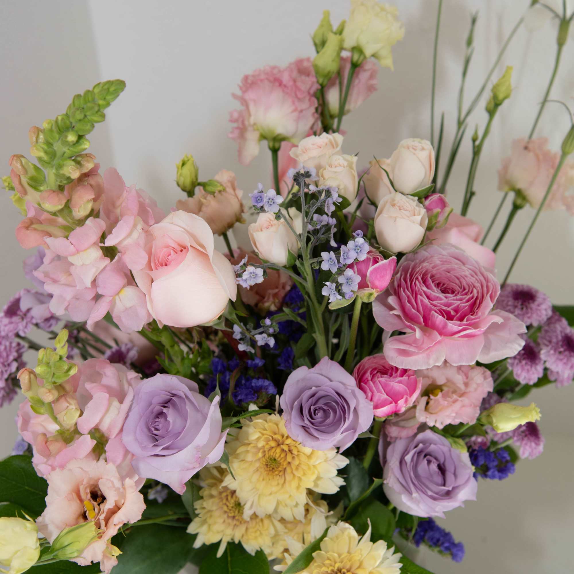 Purple roses are surrounded by pinks yellows and whimsical fly aways in