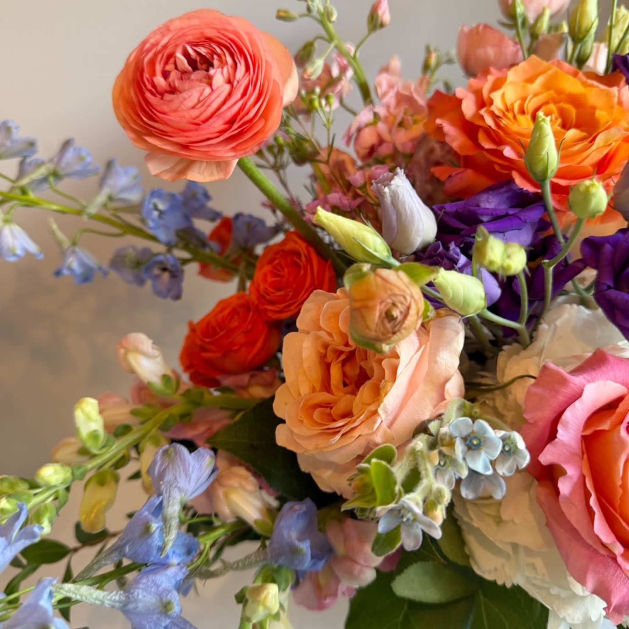 This stunning arrangement combines the fiery zest of orange, pops of purple This stunning arrangement combines the fiery zest of orange, pops of purple
