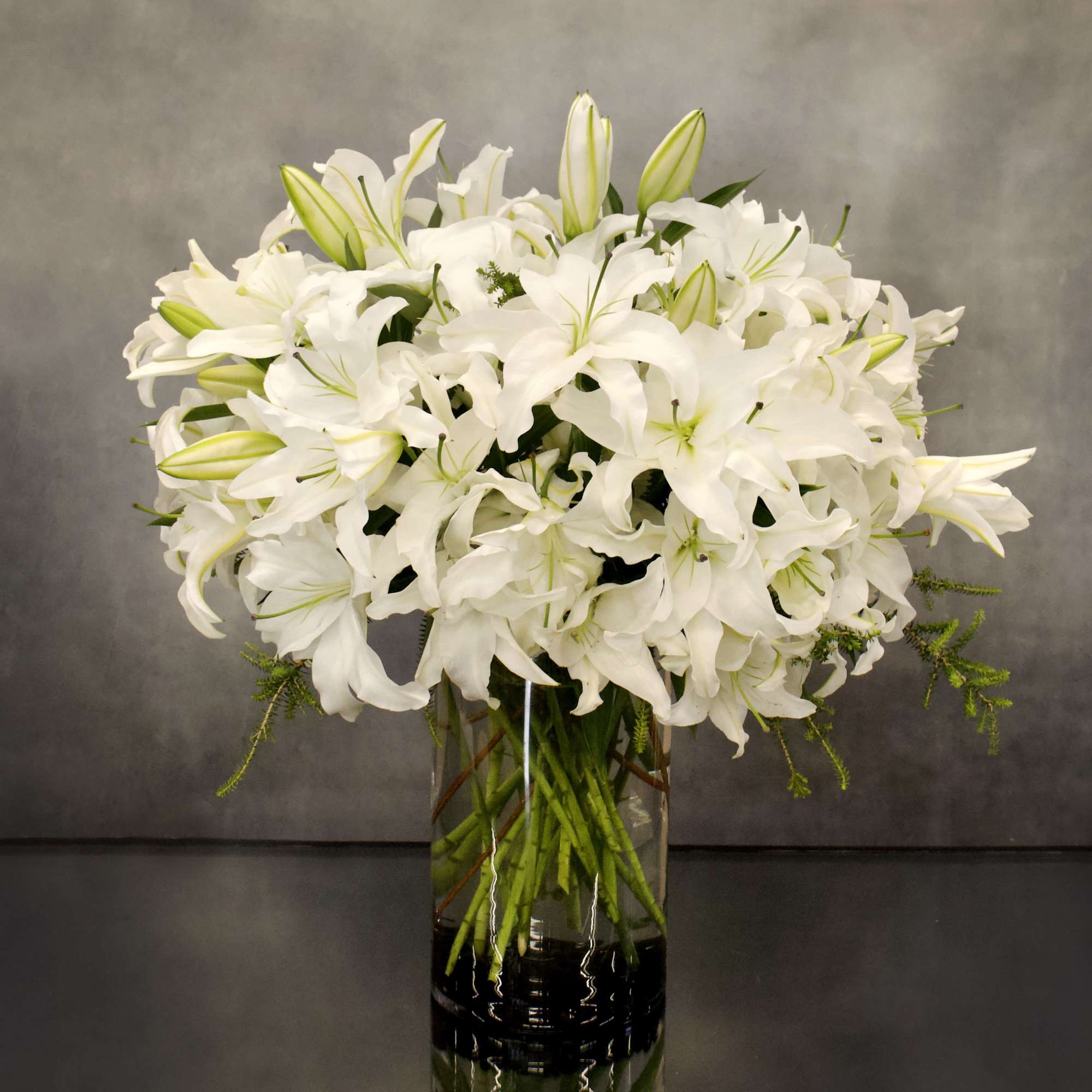 The design features white Casablanca lillies in a vase AS SHOWN PREMIUM