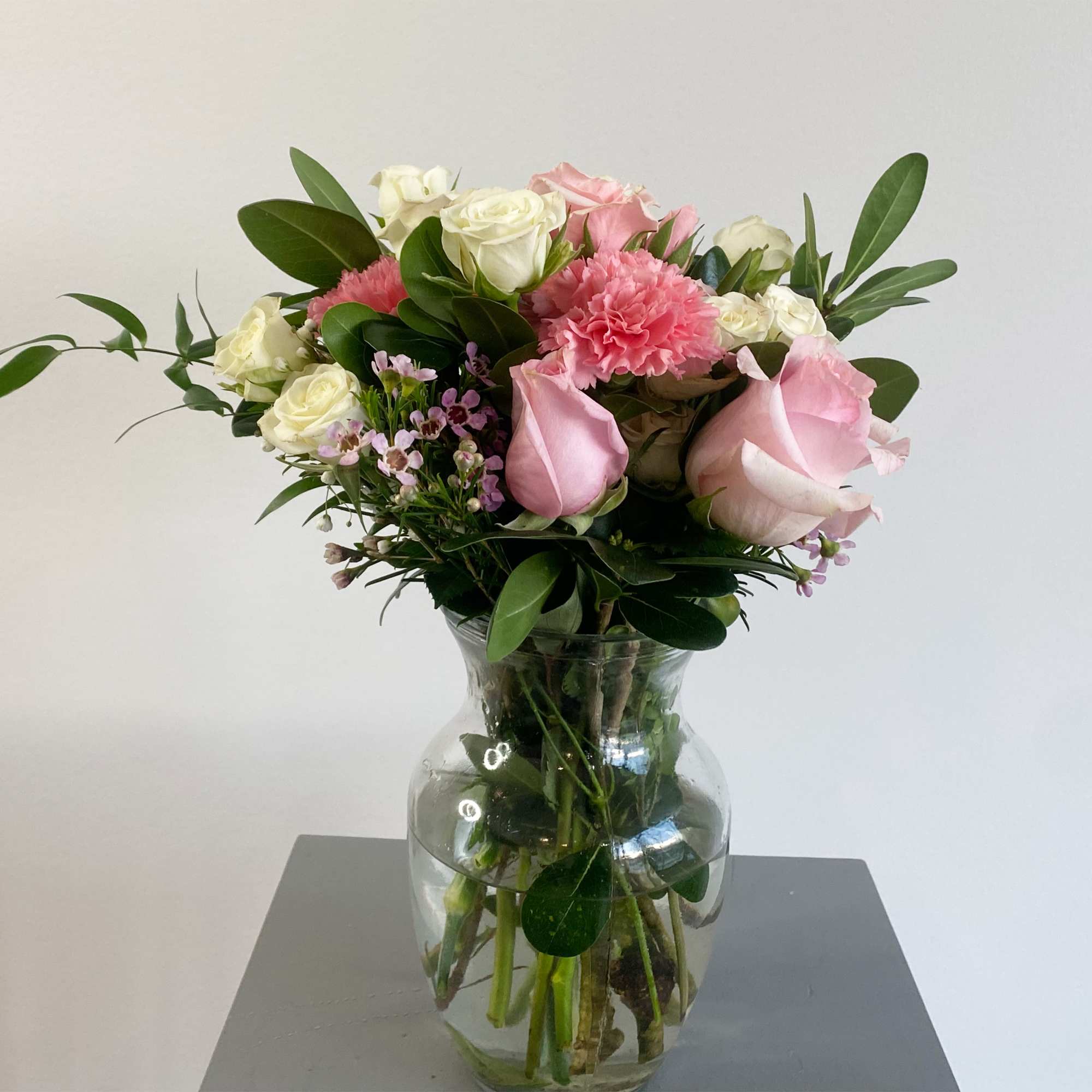 This arrangement includes pink roses, white roses, white spray roses, pink carnations