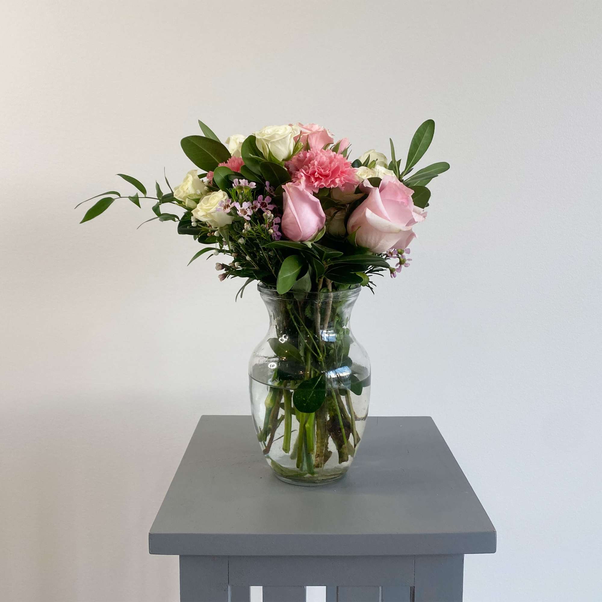 This arrangement includes pink roses, white roses, white spray roses, pink carnations