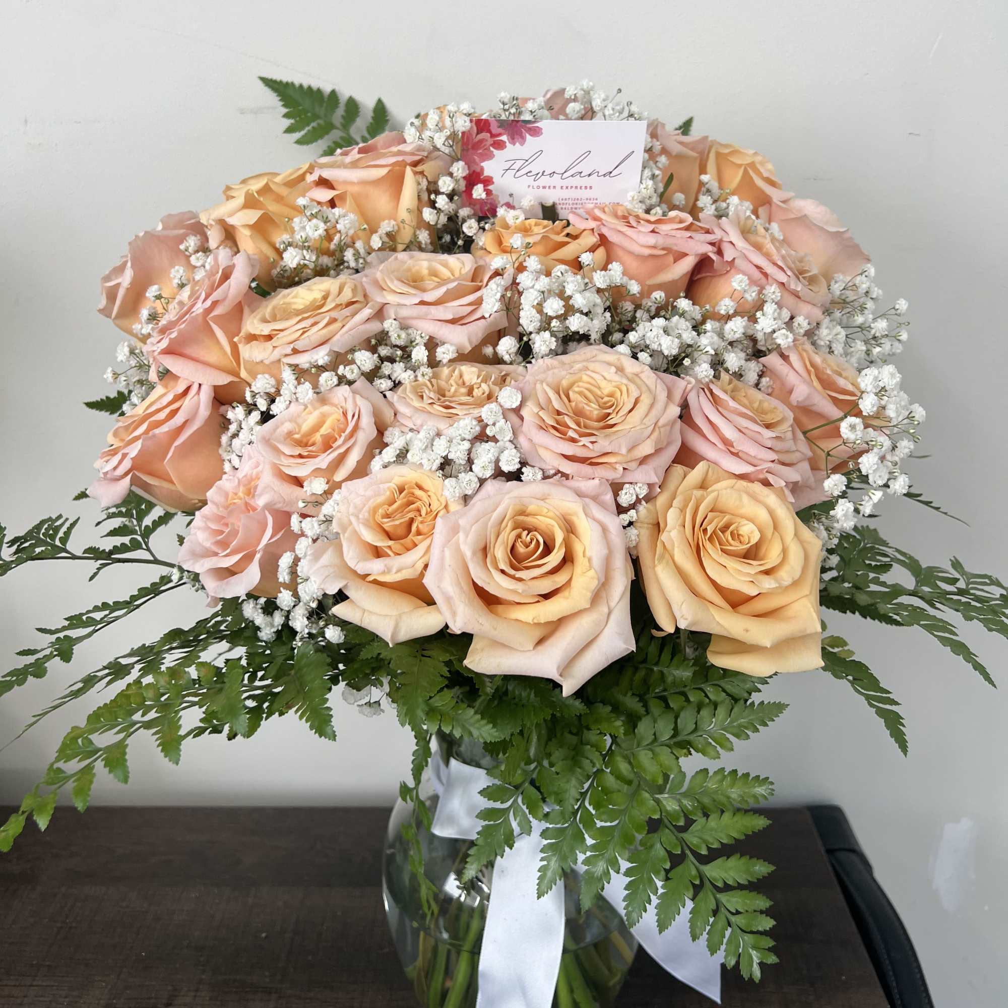 This arrangement of light pink roses, paired with green and white foliage