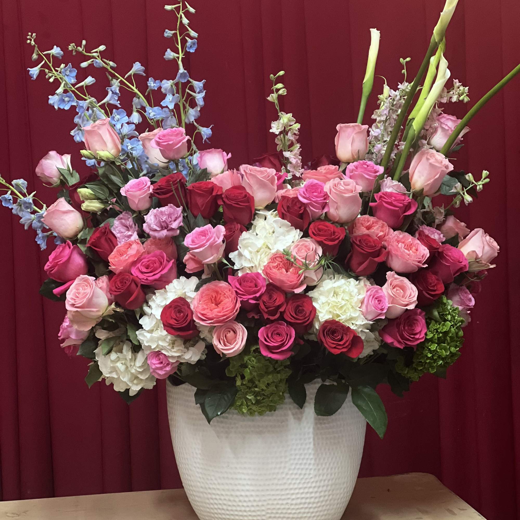 A stunning arrangement of roses in pink, hot pink, red, Cala Lilies