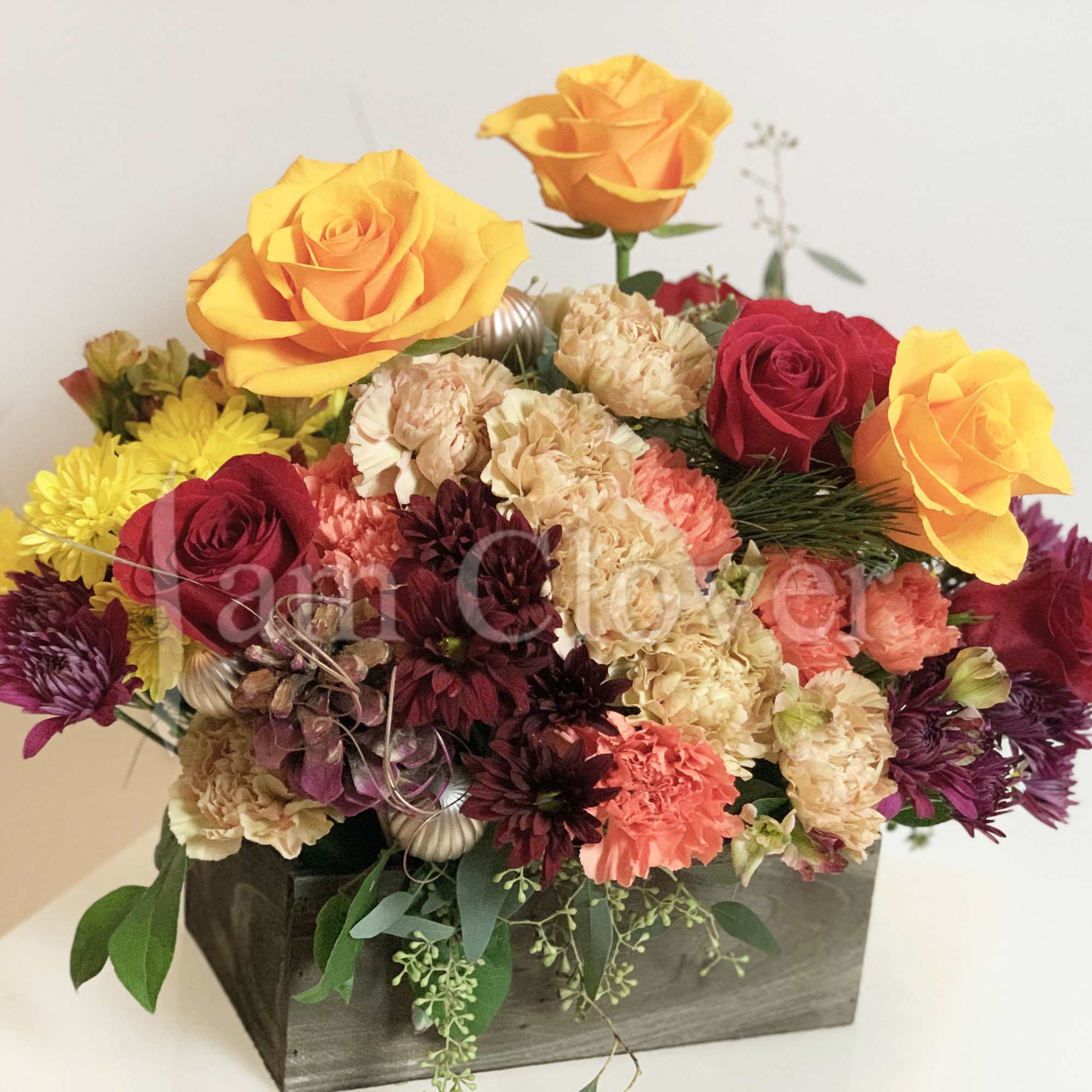 This Autumn basket arrangement features rich burgundy, warm beige, fiery red, and