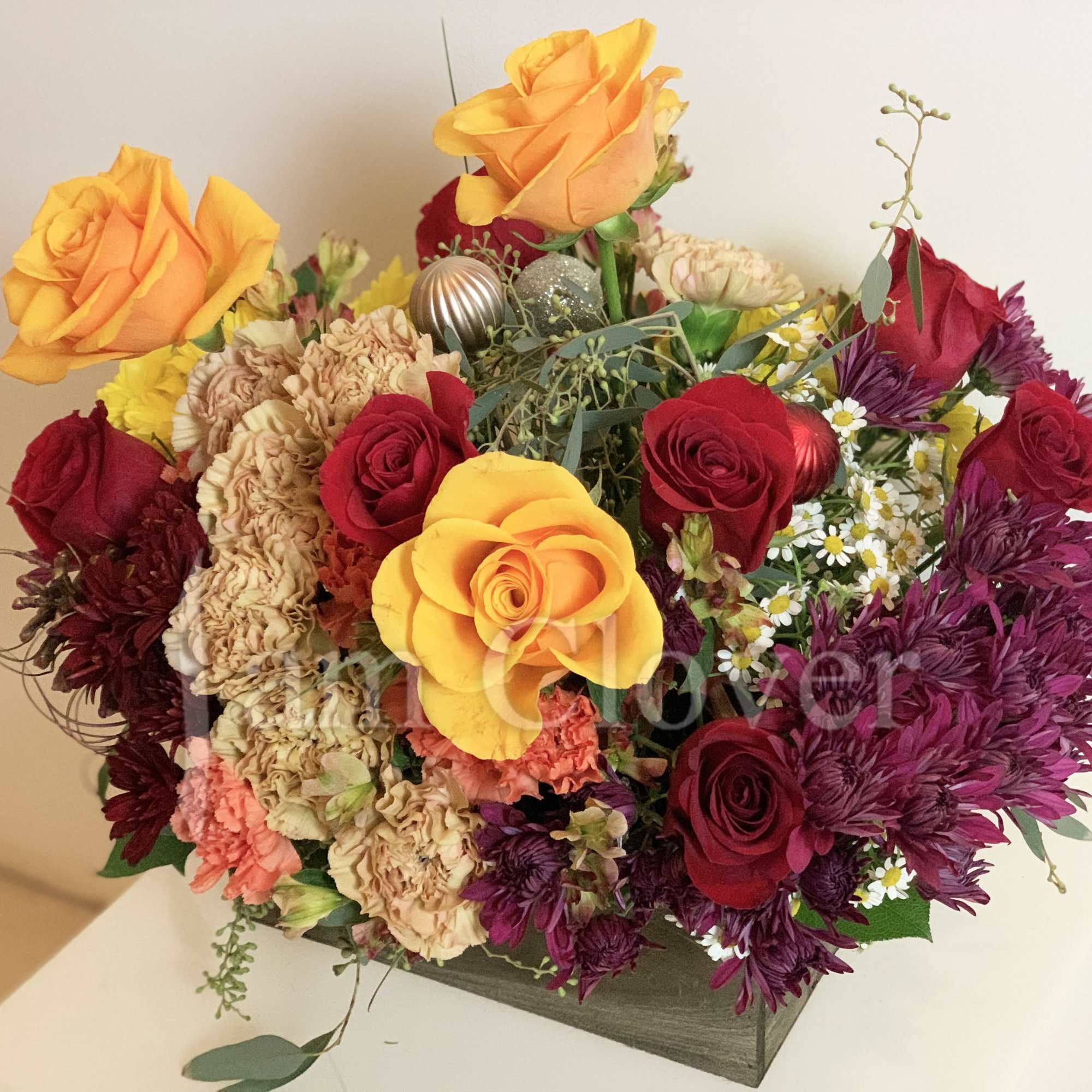 This Autumn basket arrangement features rich burgundy, warm beige, fiery red, and