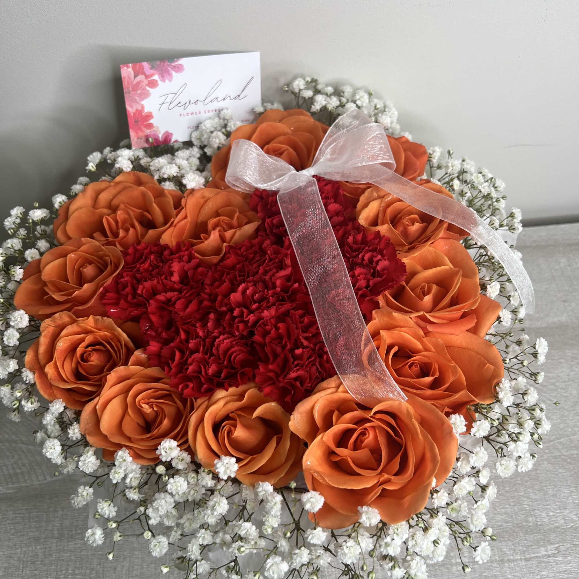 This heart-shaped arrangement combines the warmth of orange roses, the intensity of