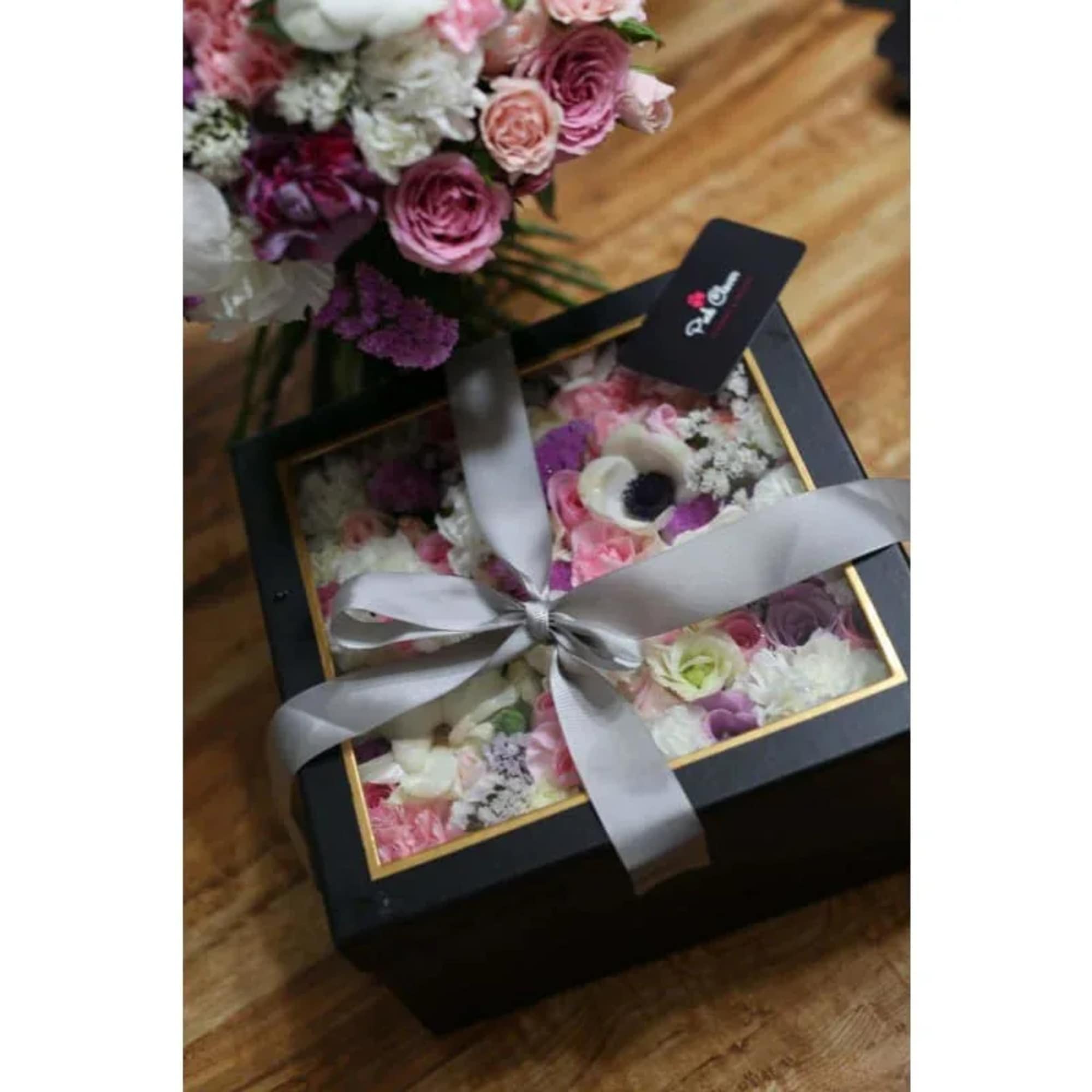 Flowers in a square box with a transparent top and a bow.