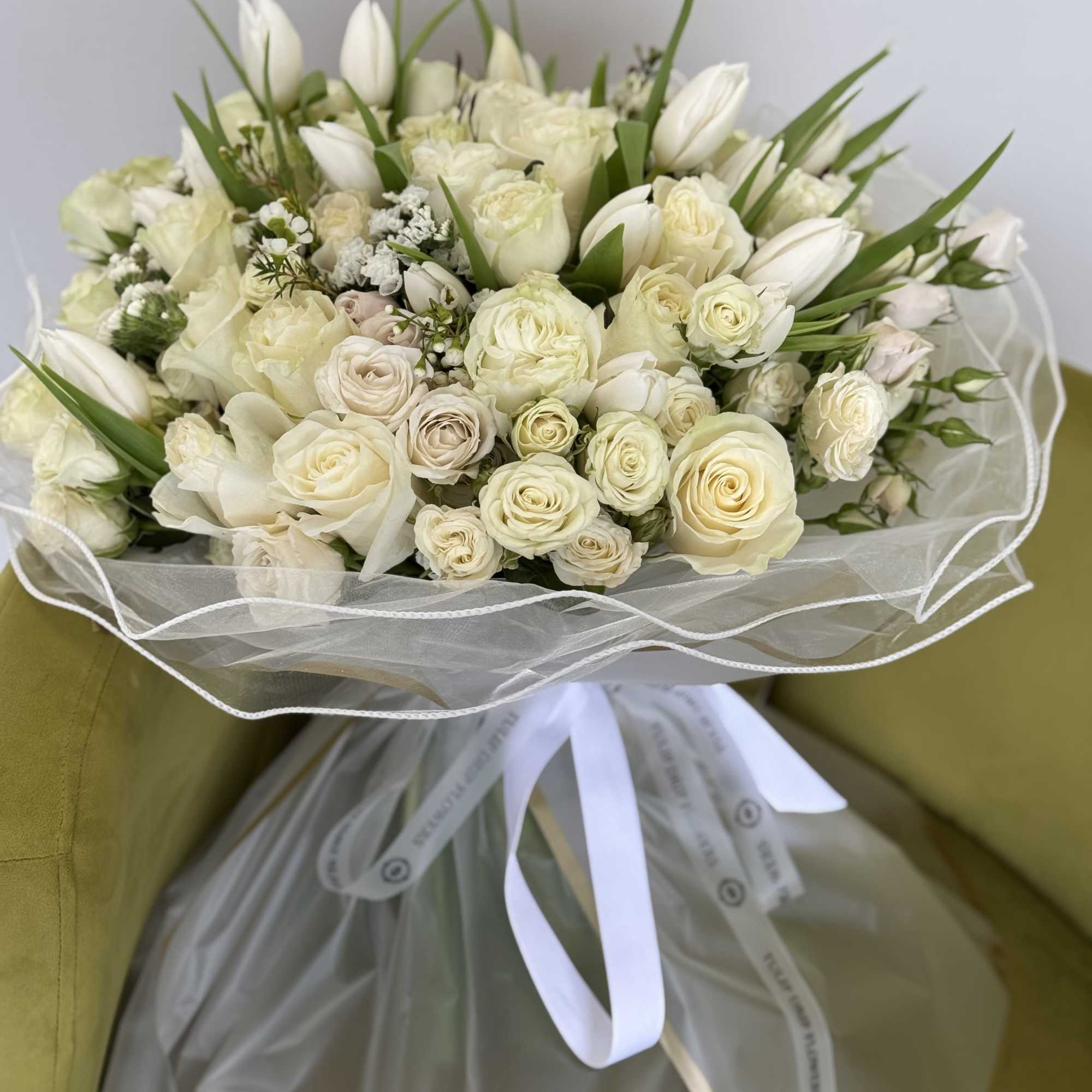 A breathtaking arrangement of pure white roses, delicate tulips, and soft accent