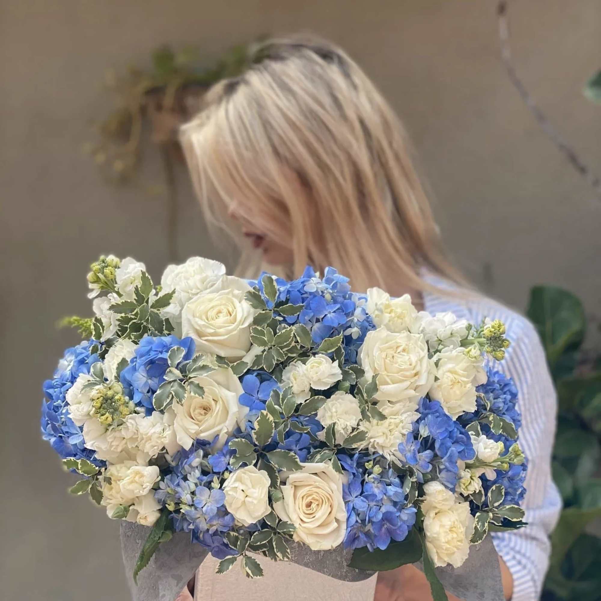 Dora is a beautiful arrangement of white roses, blue flowers, hydrangea, stachys