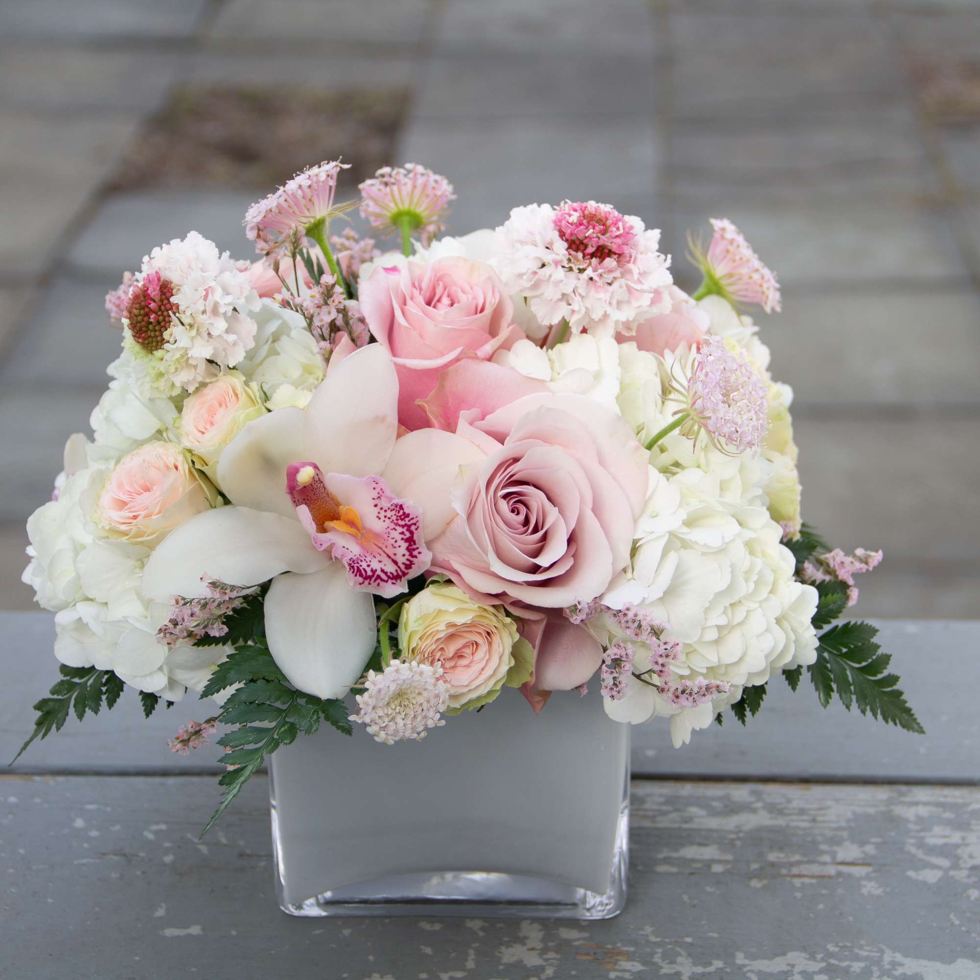 A compact, more modern style arrangement featuring roses, spray roses, hydrangea, and A compact, more modern style arrangement featuring roses, spray roses, hydrangea, and