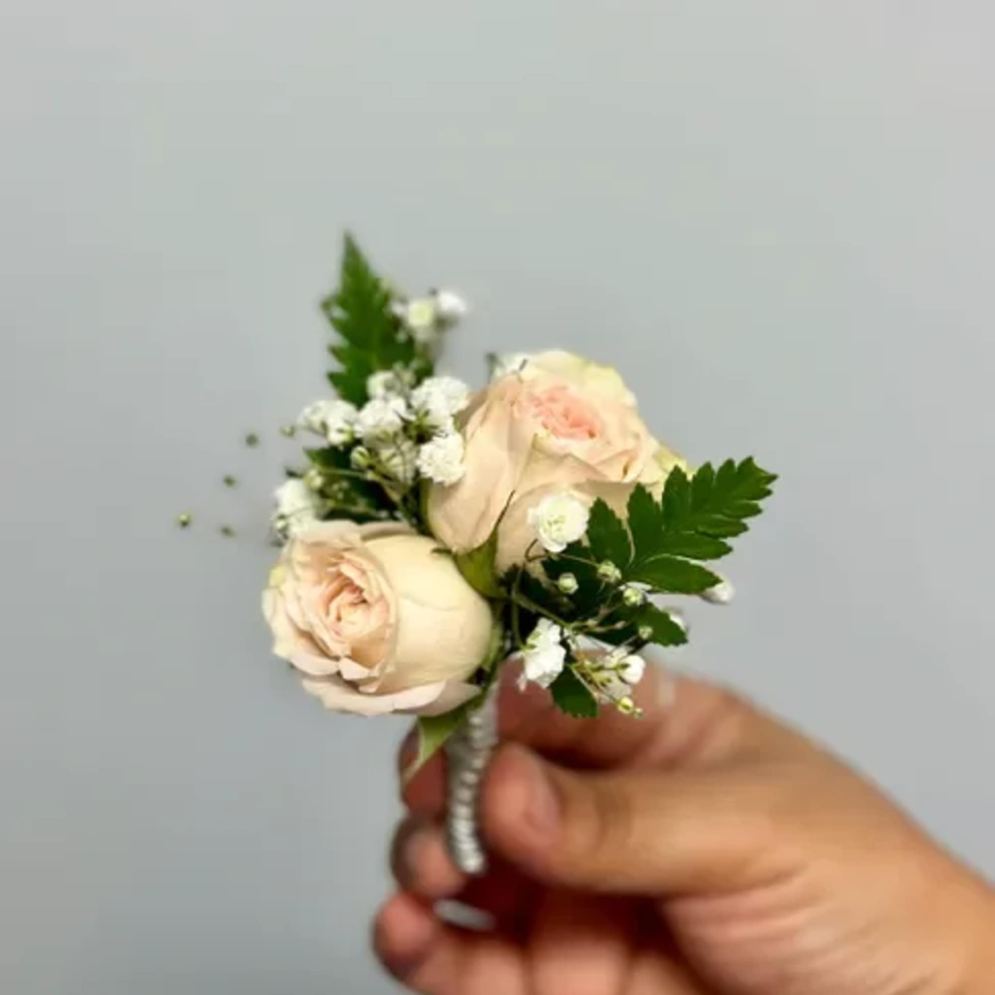 The Bam Boutonniere made with champagne/light pink center spray roses and baby&#039;s