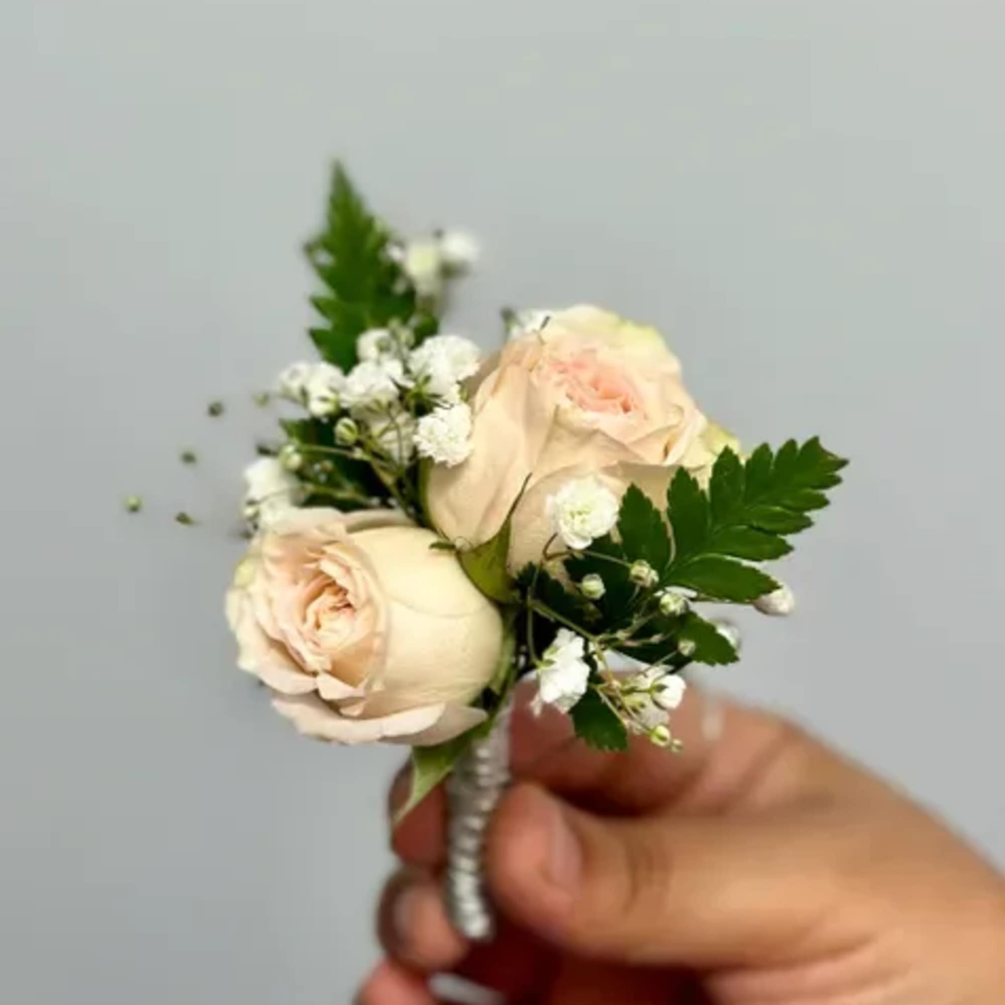 The Bam Boutonniere made with champagne/light pink center spray roses and baby&#039;s