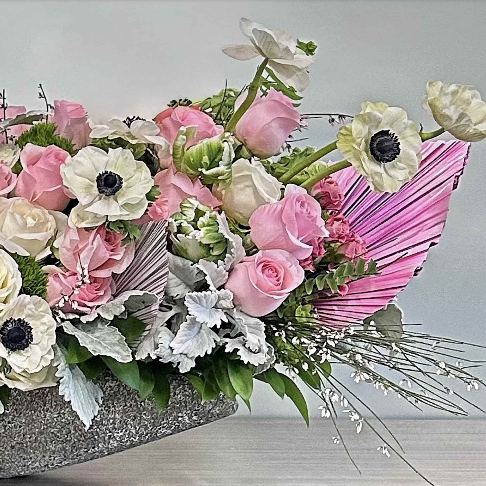 A modern floral arrangement featuring pink orchids, blush and ivory roses, white