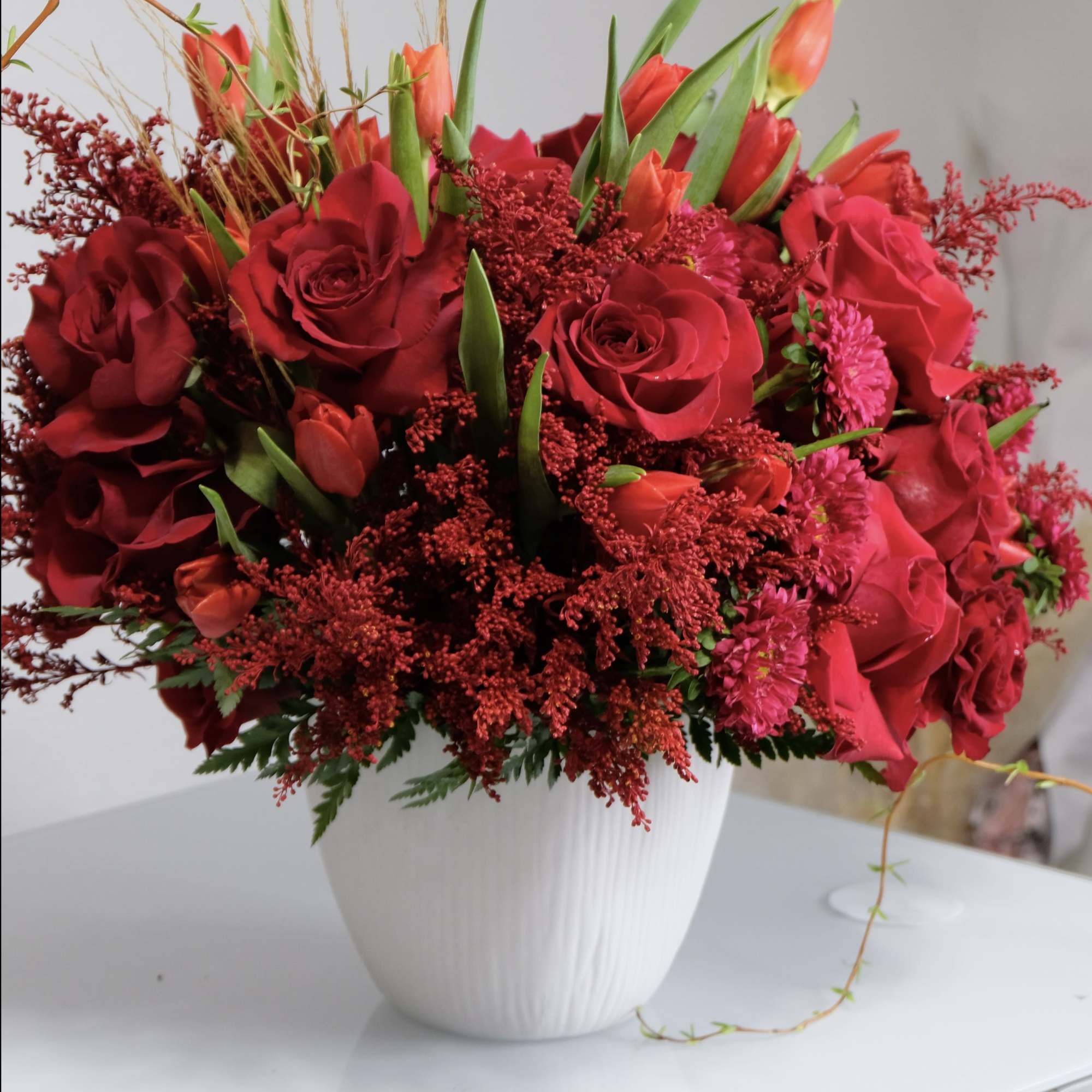 A vibrant arrangement of fresh red roses, tulips, and seasonal blooms in