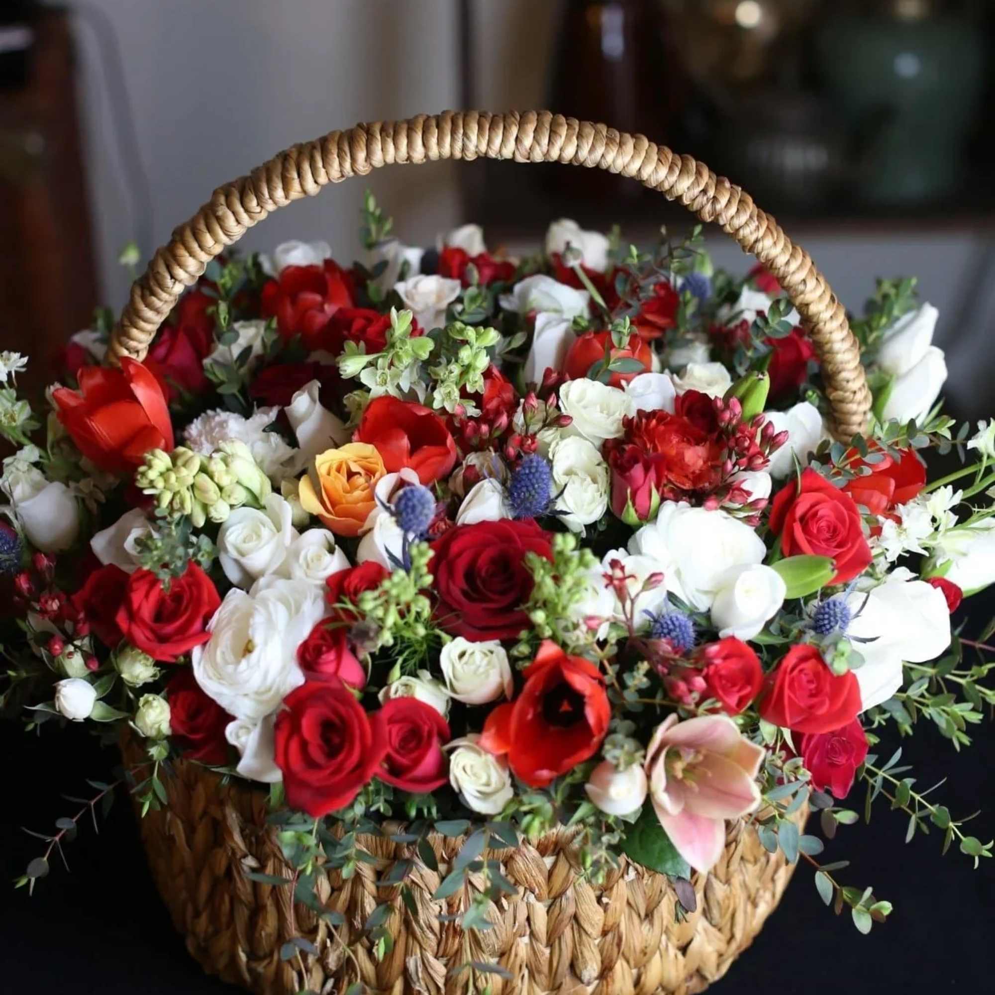 The basket of roses, ranunculus, delphinium, thistle and tulips flowers with Baby