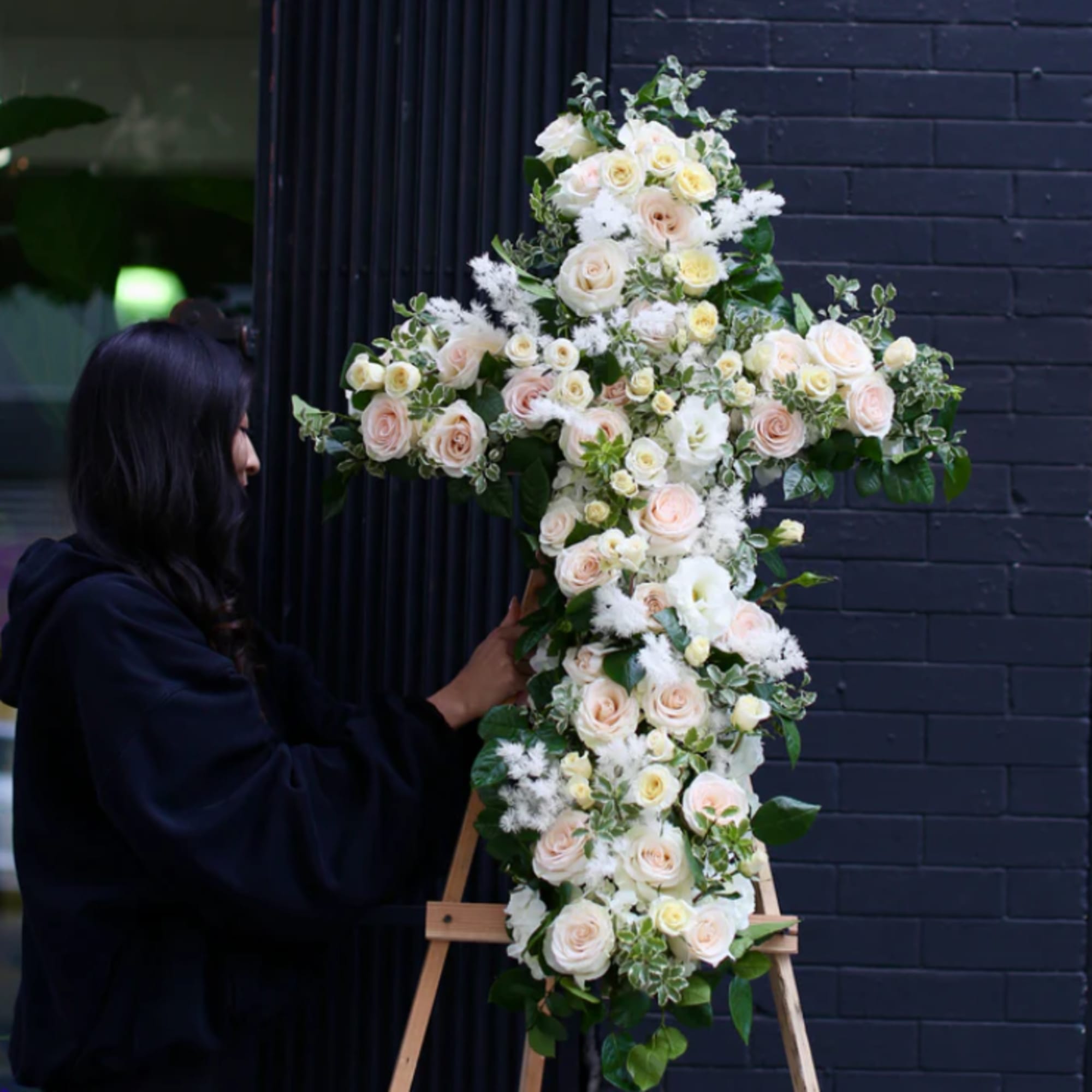 A solemn tribute featuring roses and lisianthus arranged in the shape of