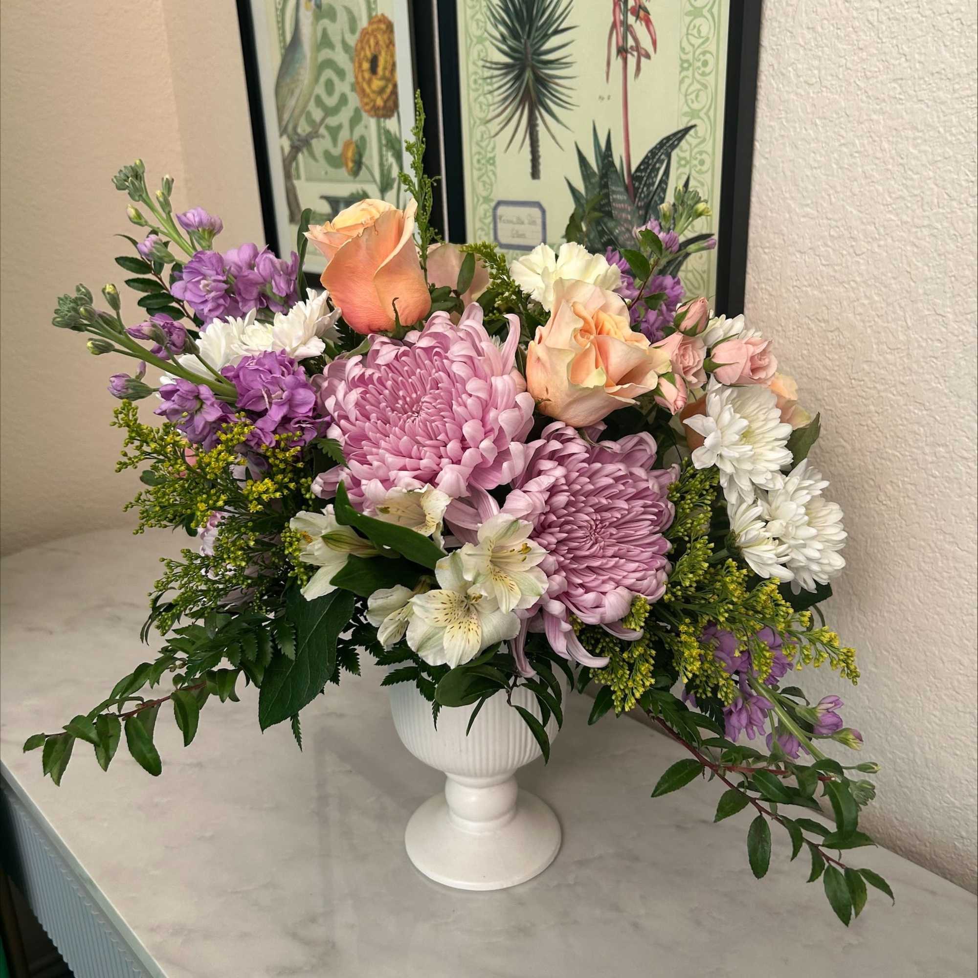 A lush and elegant floral arrangement that combines soft pastels with rich A lush and elegant floral arrangement that combines soft pastels with rich