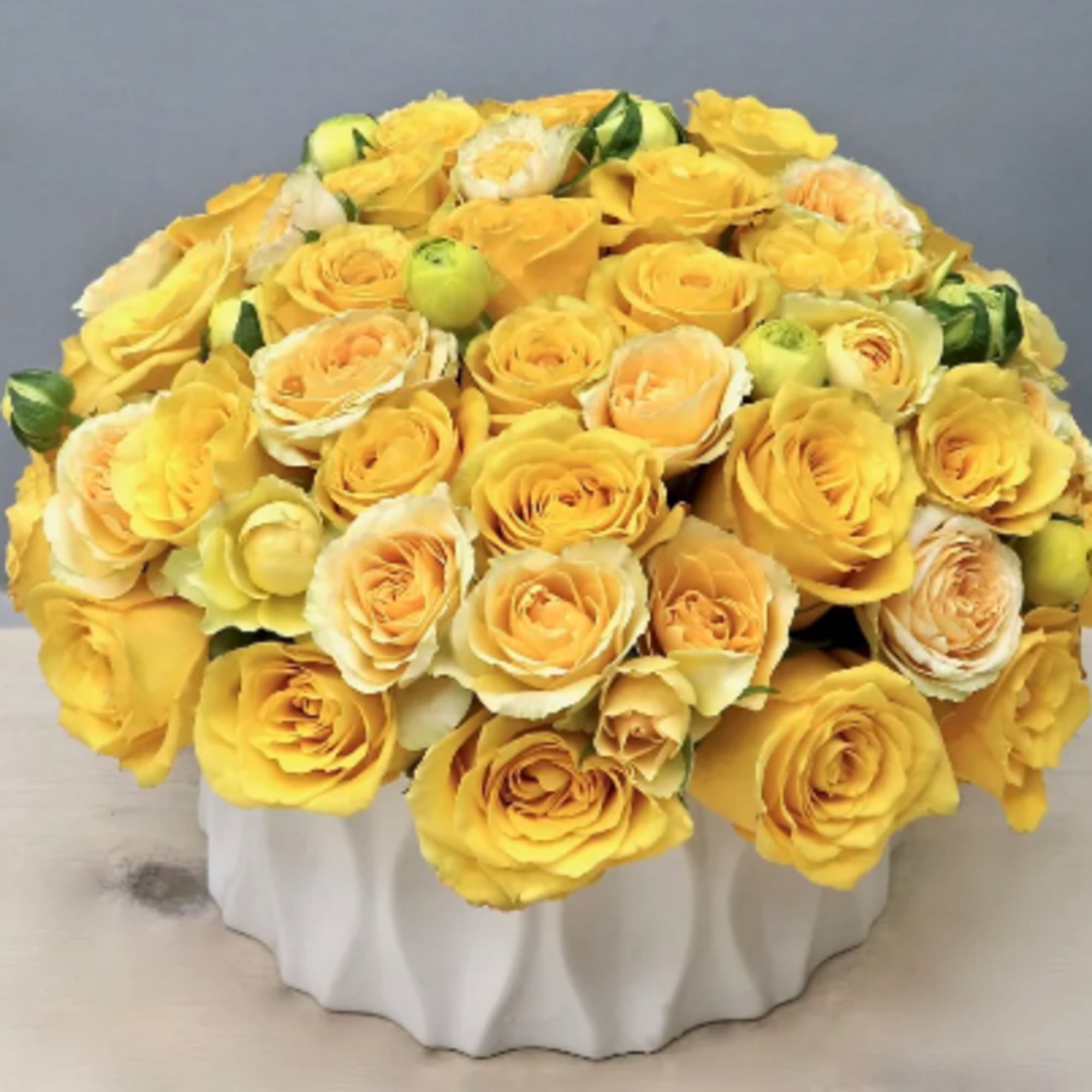 Over two dozen joyful yellow Roses in a round vase. These bright